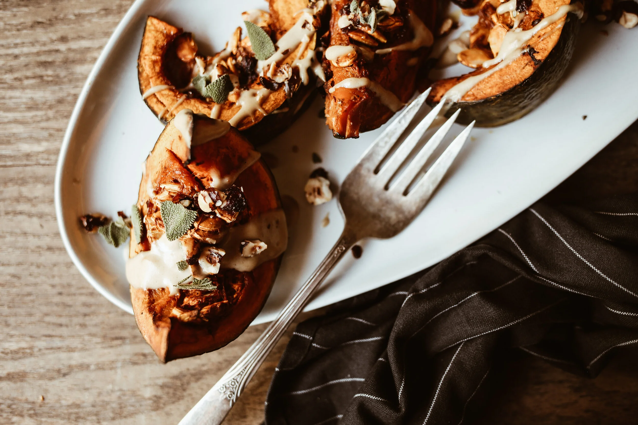 Raw kabocha squash cut into thick wedges with seeds removed, arranged on a cutting board with a spoon nearby