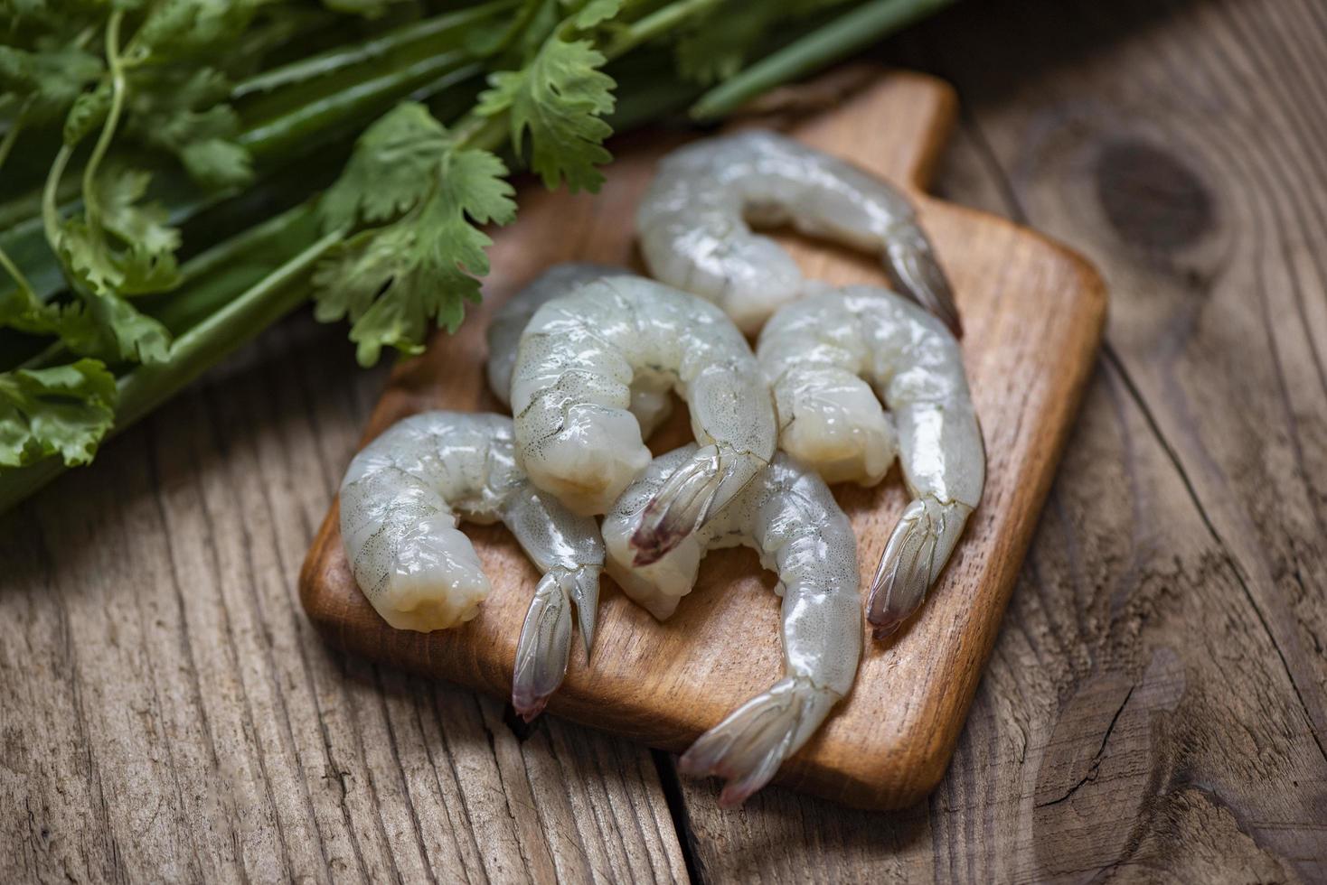 Raw peeled and deveined shrimp arranged on a cutting board with a chef's knife nearby