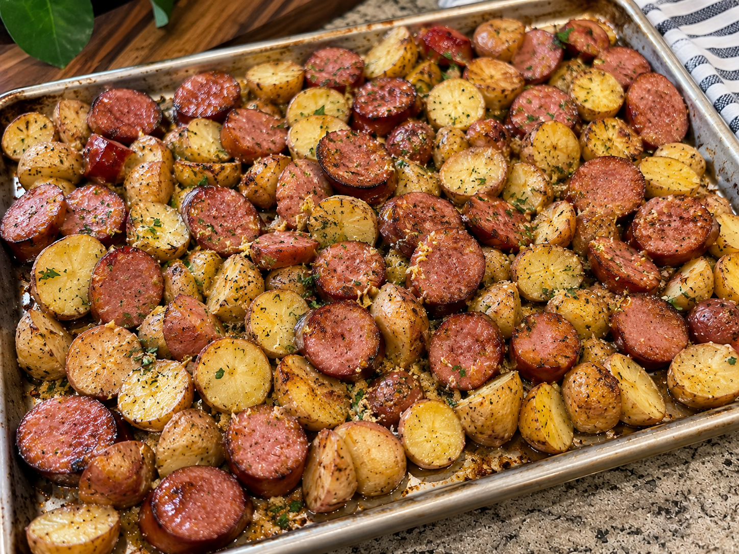 Raw pork sausages, Yukon Gold potatoes, yellow onions, butter, milk, flour, and fresh thyme arranged on a light kitchen counter in a home kitchen