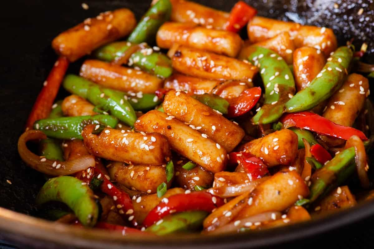 Rice cakes browning in a hot skillet with a light sheen of oil, showing golden spots forming on the surface