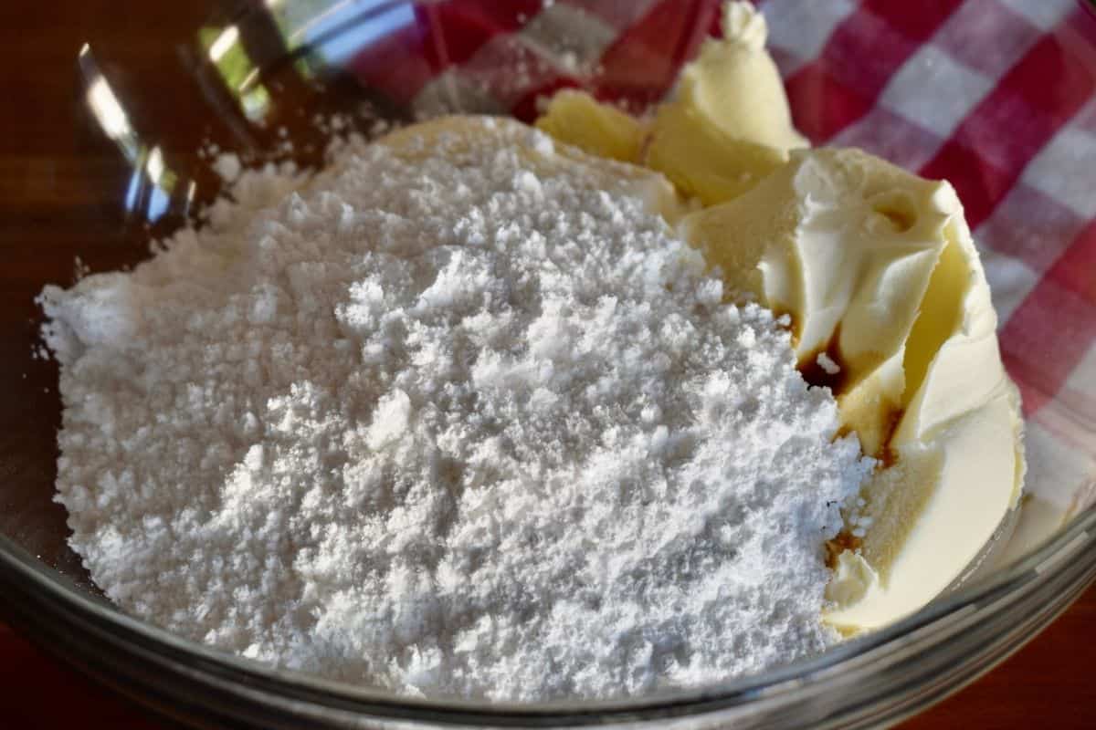 Ricotta, mascarpone, powdered sugar, vanilla, and chocolate chips arranged on a kitchen counter with a mixing bowl