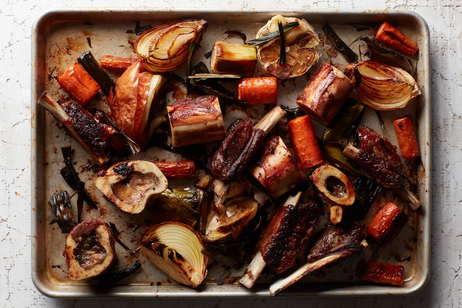 Roasted beef bones browned on a rimmed sheet pan with caramelized bits