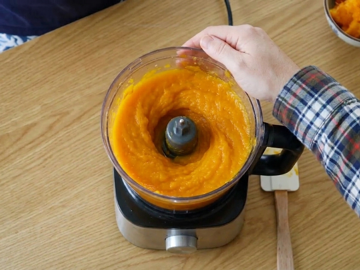 Roasted pumpkin flesh being blended into a smooth purée in a food processor