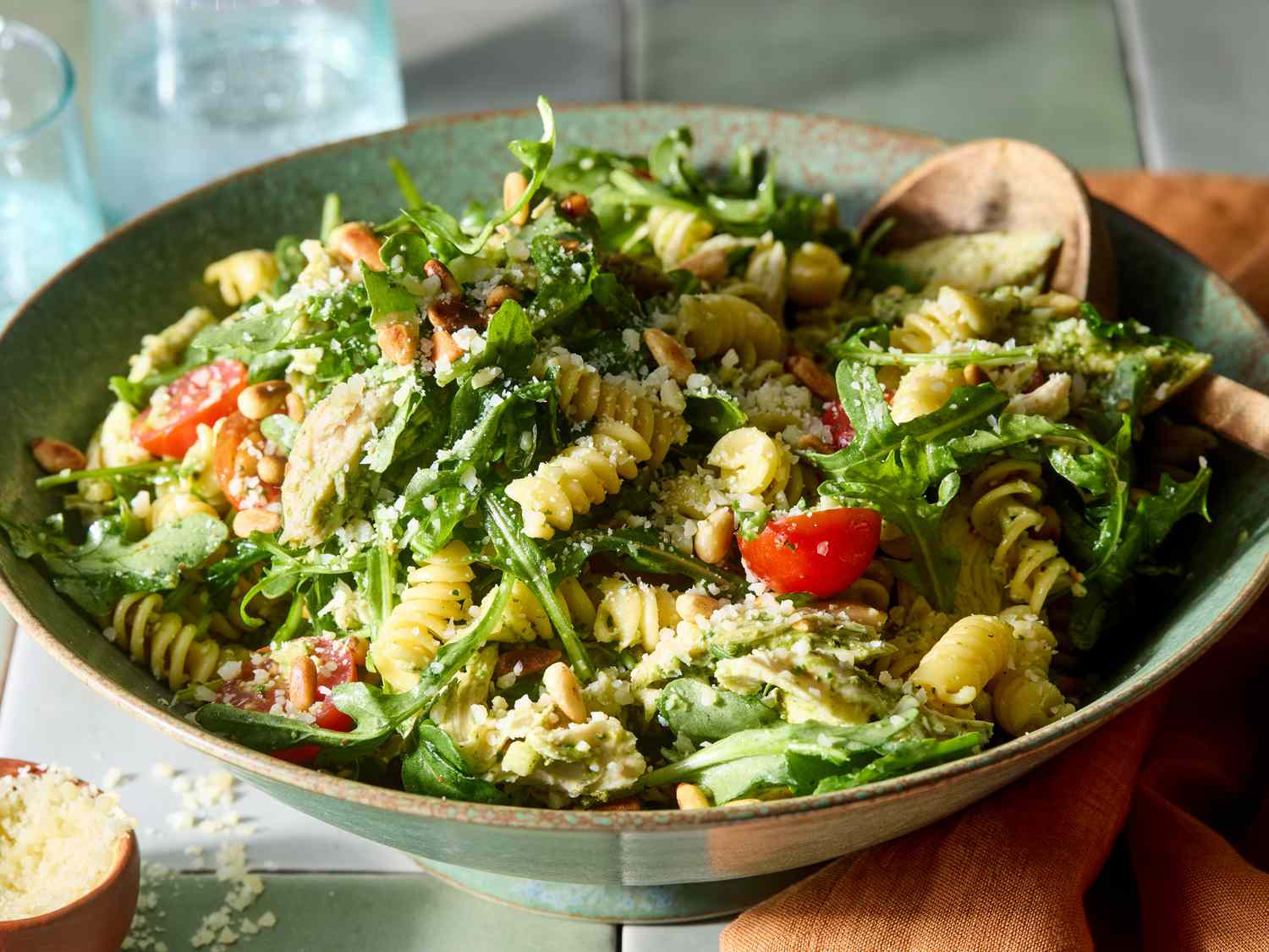 Rotini pasta, basil pesto, chicken breast, baby spinach, Parmesan, lemon, garlic, and cream arranged on a kitchen counter with soft natural light