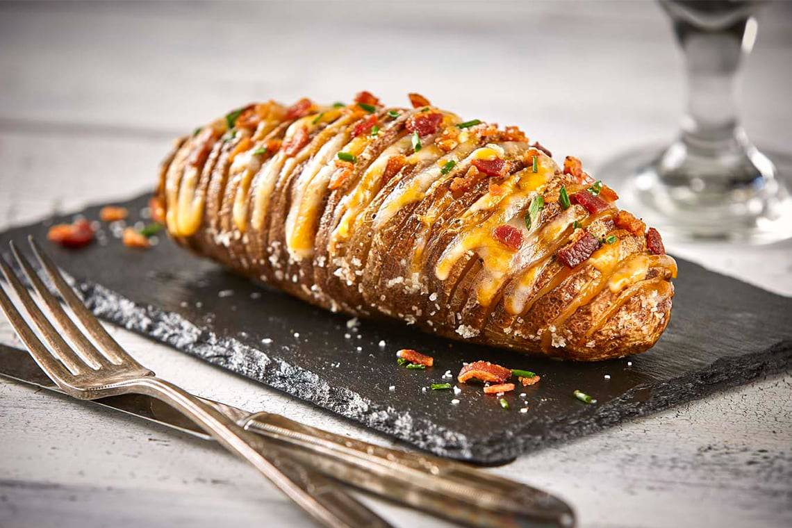 Russet potatoes, shredded cheddar, Parmesan, sour cream, cream cheese, garlic, and sun-dried tomatoes arranged together before cooking.