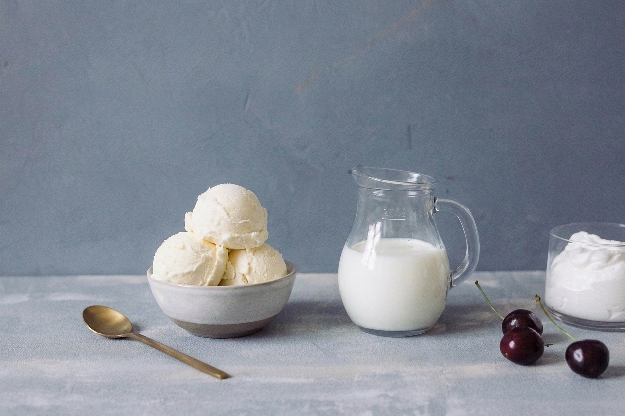 Scoops of vanilla ice cream and a small pitcher of milk on a kitchen counter ready for making milkshakes