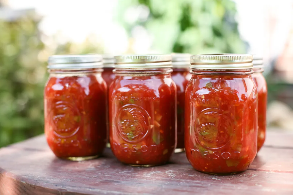 Sealed half-pint jars of homemade red salsa cooling on a kitchen counter