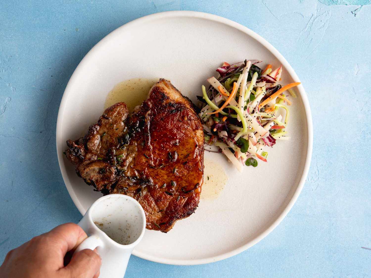 Seared pork shoulder steaks resting on a plate with a browned crust and a little pan juice