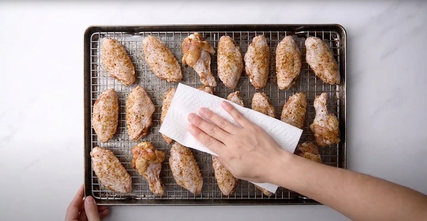 Seasoned chicken wings arranged in a single layer on a wire rack set over a sheet pan