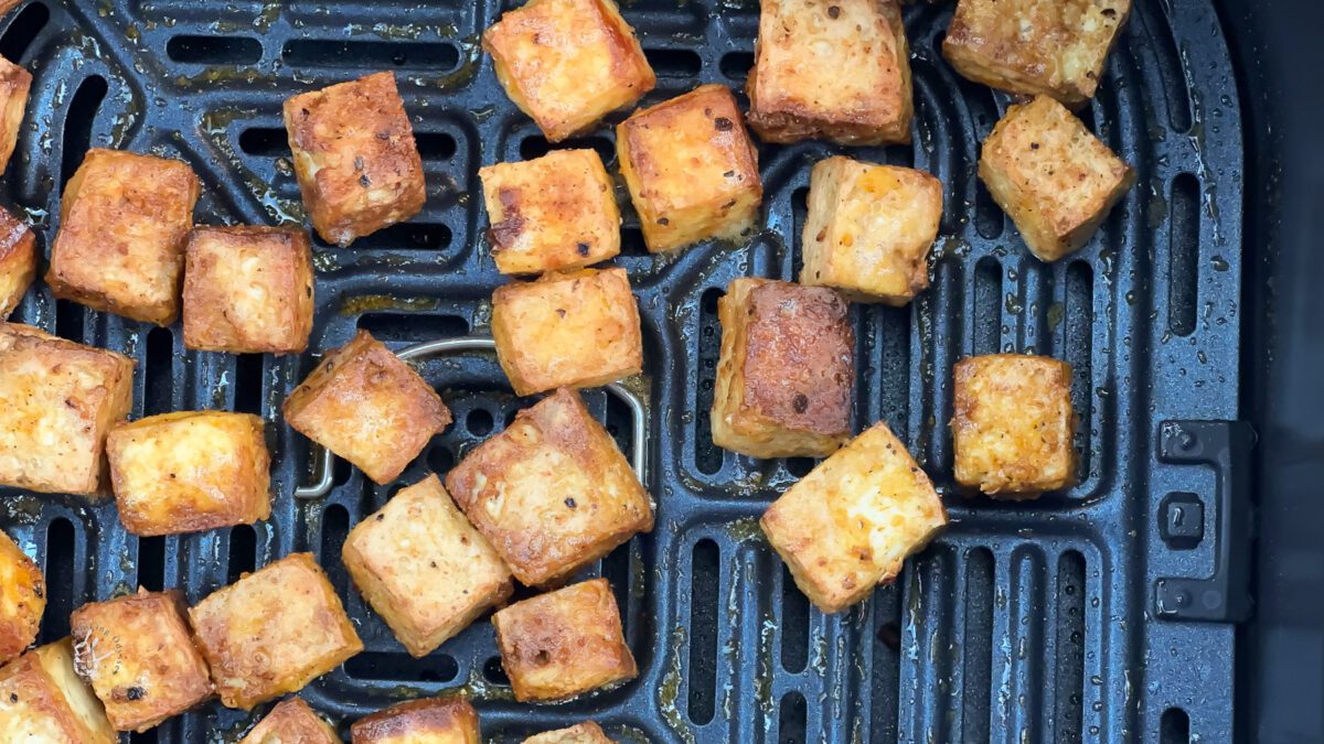 Seasoned tofu cubes in a single layer in an air fryer basket