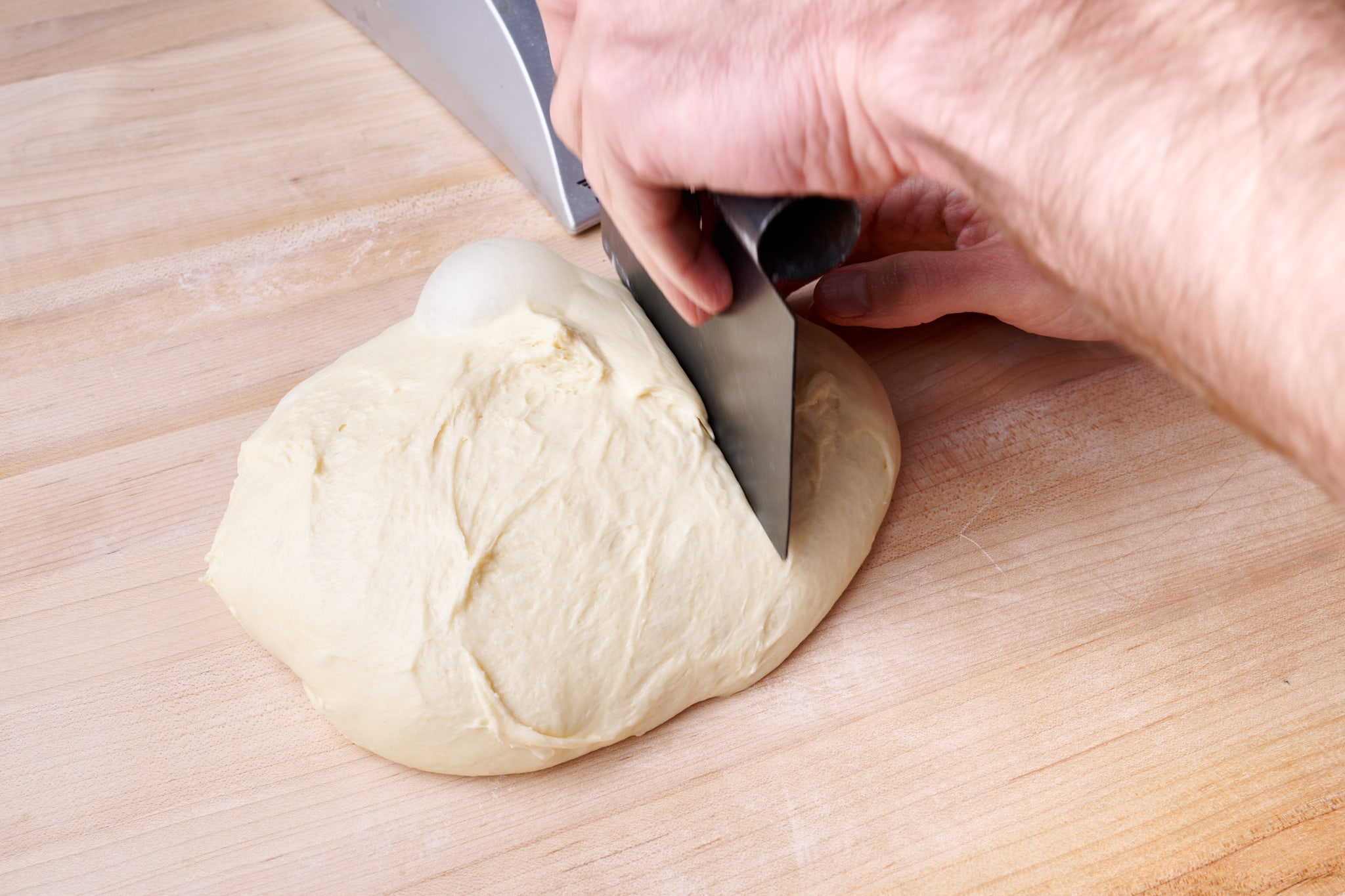 Shokupan dough rolled into a tight log on a lightly floured work surface, ready to go into the loaf pan