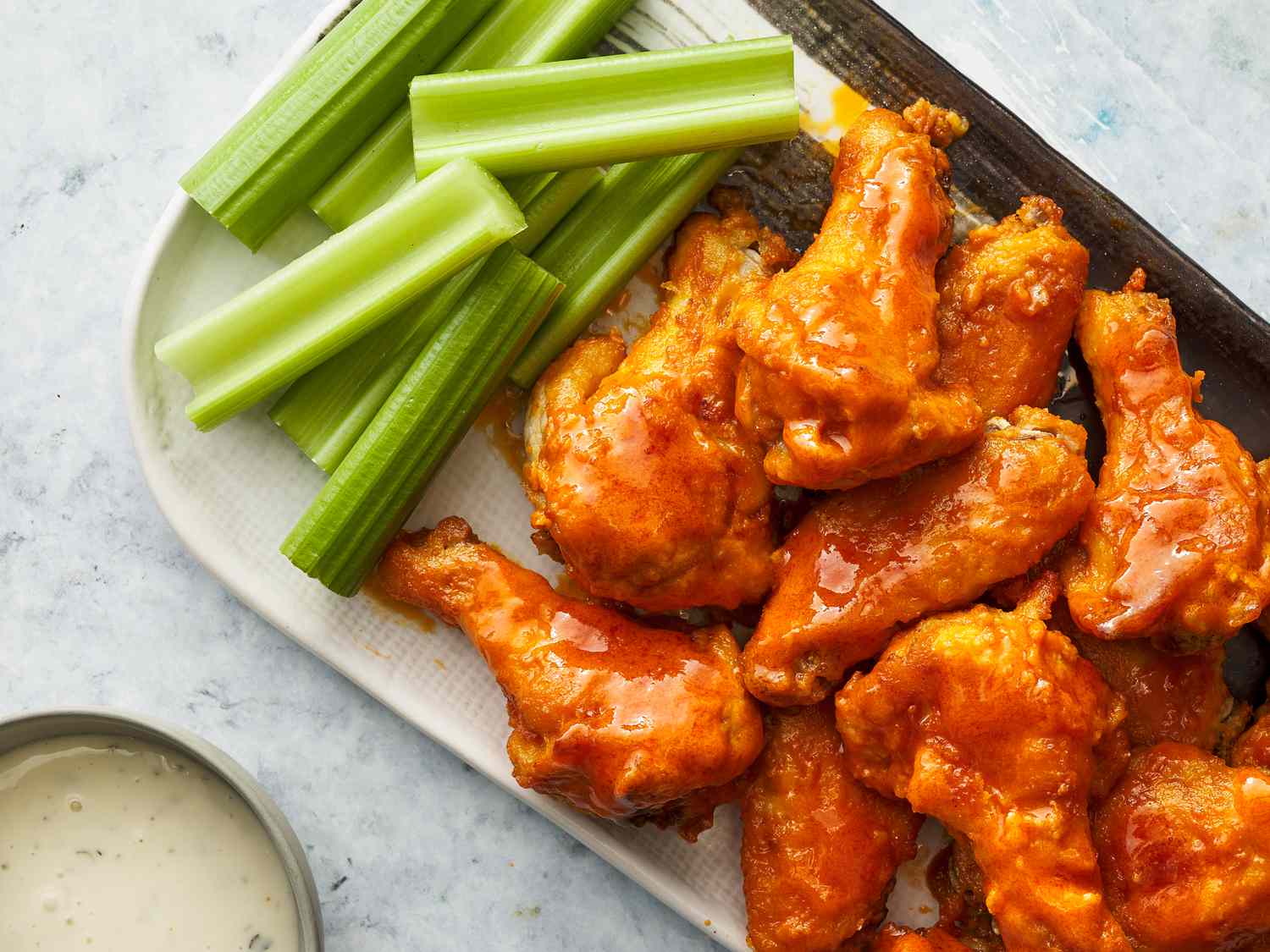 Shredded chicken coated in glossy buffalo sauce in a mixing bowl with a spoon