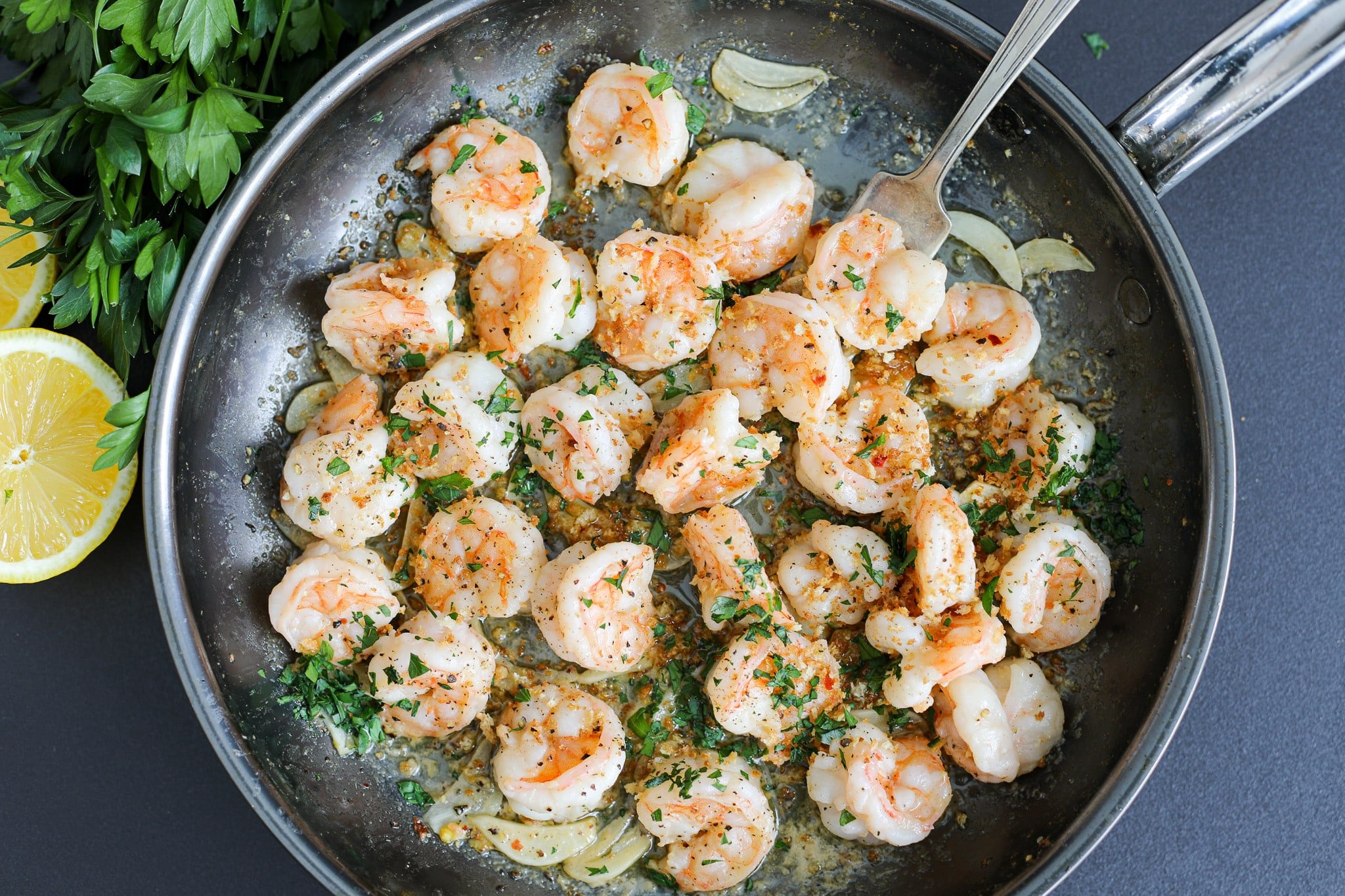 Shrimp being sautéed in a skillet with garlic and red pepper flakes