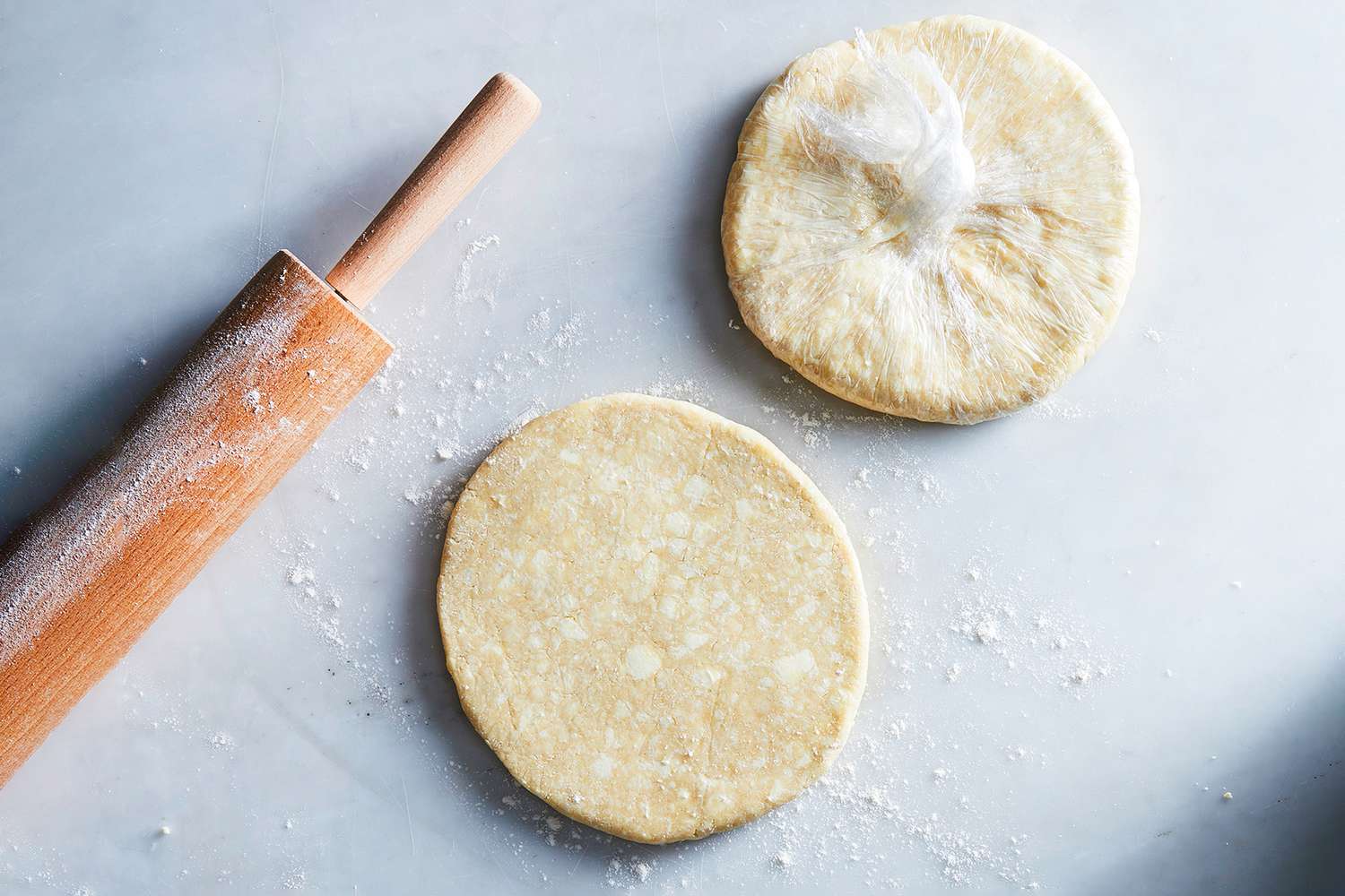 Six wrapped dough discs resting on a cutting board on a kitchen counter