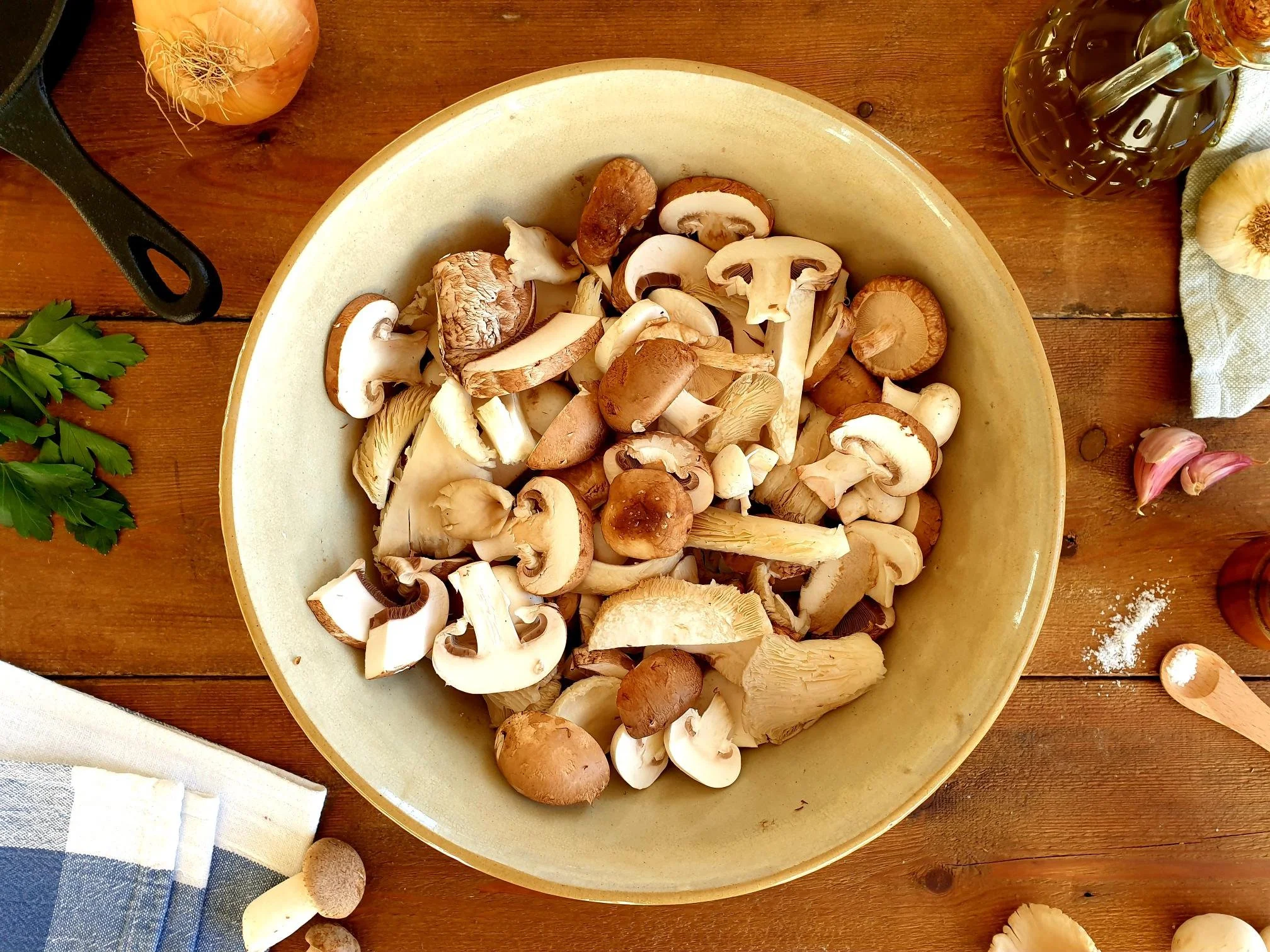 Sliced mushrooms, thinly sliced onions, and minced garlic prepped in separate bowls on a kitchen counter under soft natural light