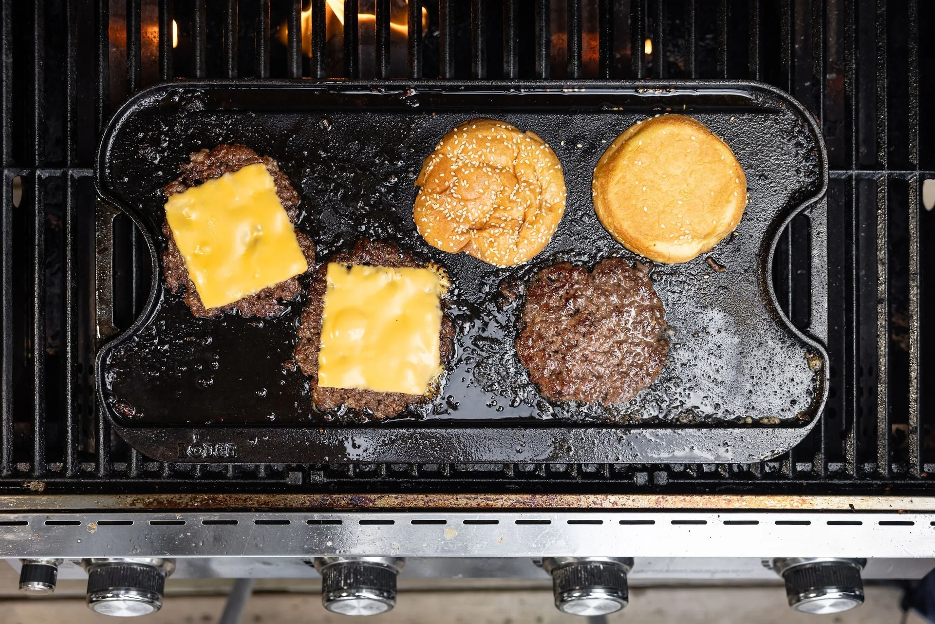Smash burger slider patties sizzling in a cast iron skillet with crisp browned edges