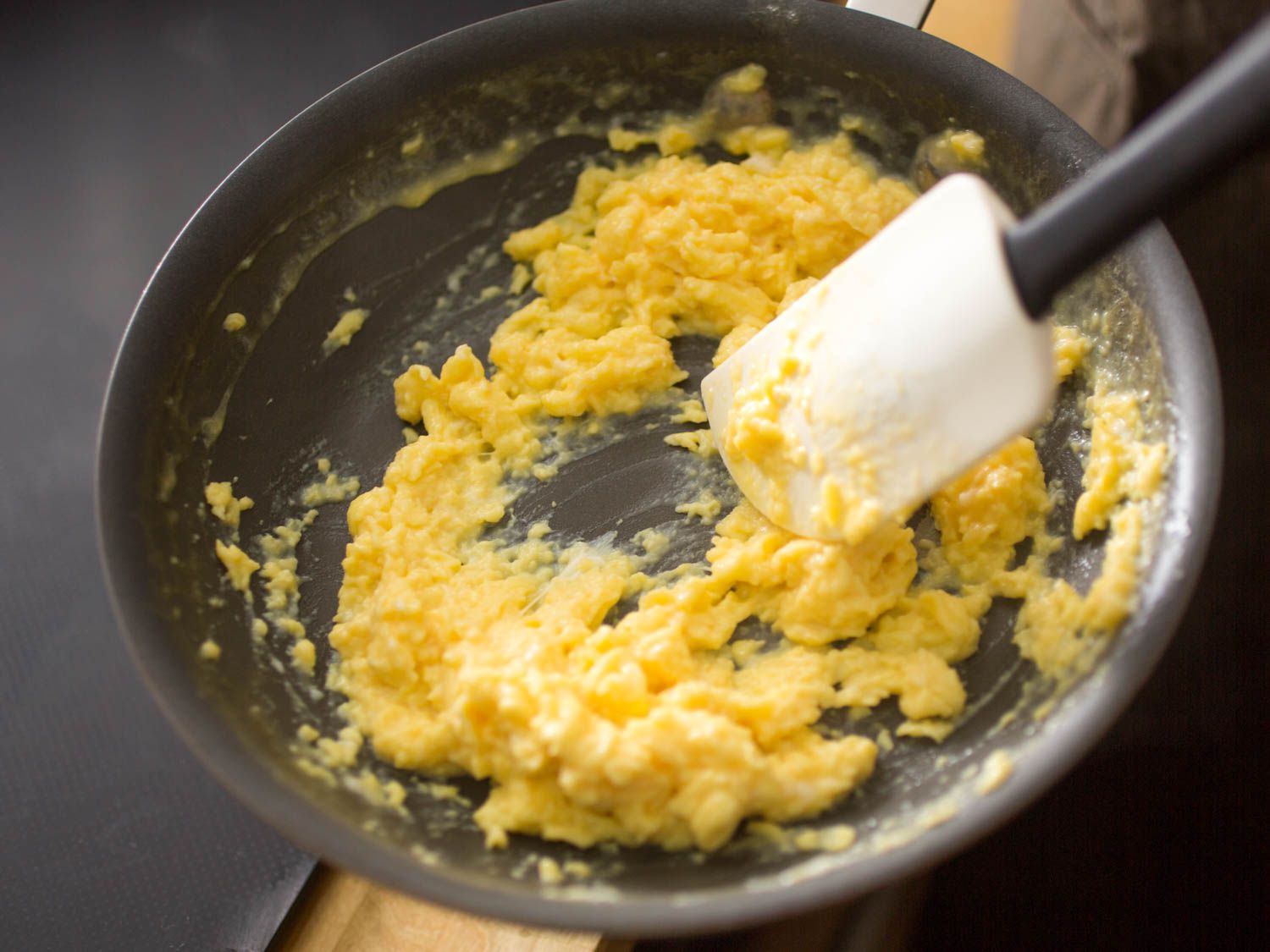 Soft scrambled eggs cooking in a hot skillet with a spatula folding them into tender curds