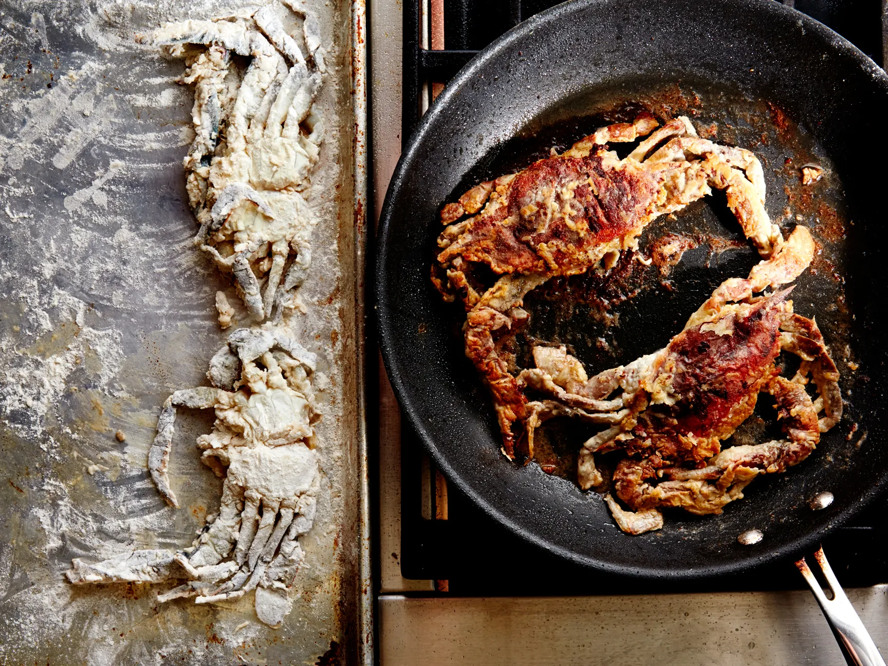 Soft shell crabs sizzling in a cast iron skillet with bubbling oil as the golden coating forms at the edges