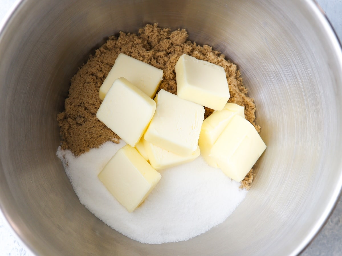 Softened butter and brown sugar in a mixing bowl with a wooden spoon on a kitchen counter