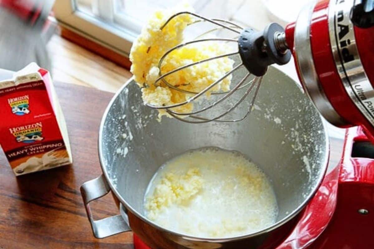 Softened butter being whipped in a stand mixer bowl with the paddle attachment, creating a pale creamy texture