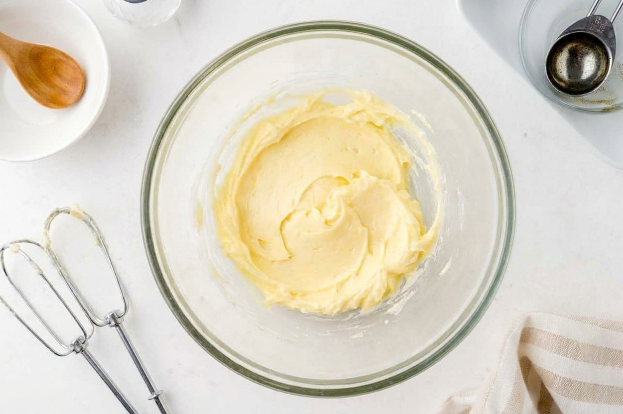Softened butter in a large mixing bowl with a hand mixer nearby on a bright kitchen counter