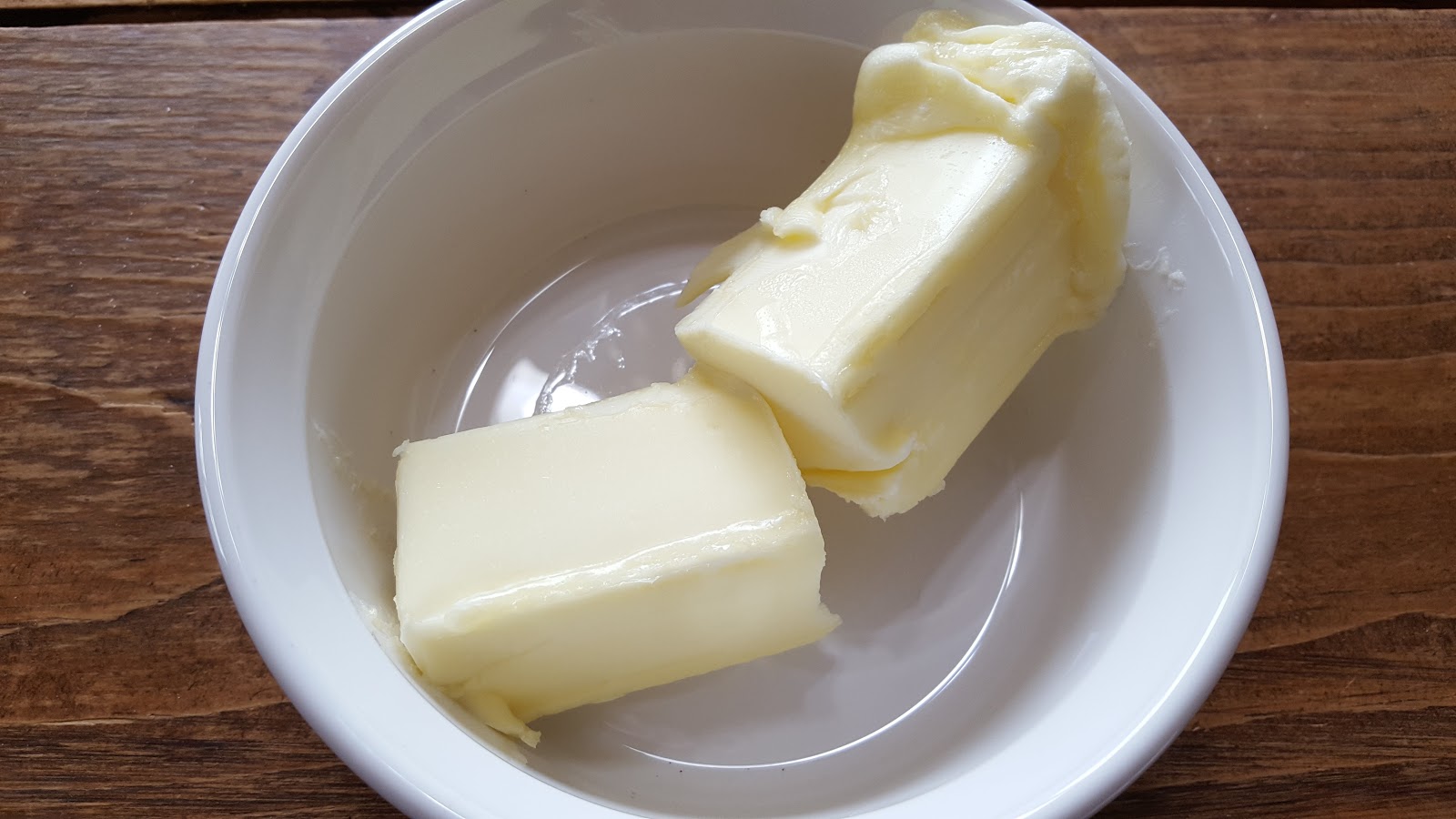 Softened butter in a mixing bowl with a hand mixer nearby on a warm, homey kitchen counter