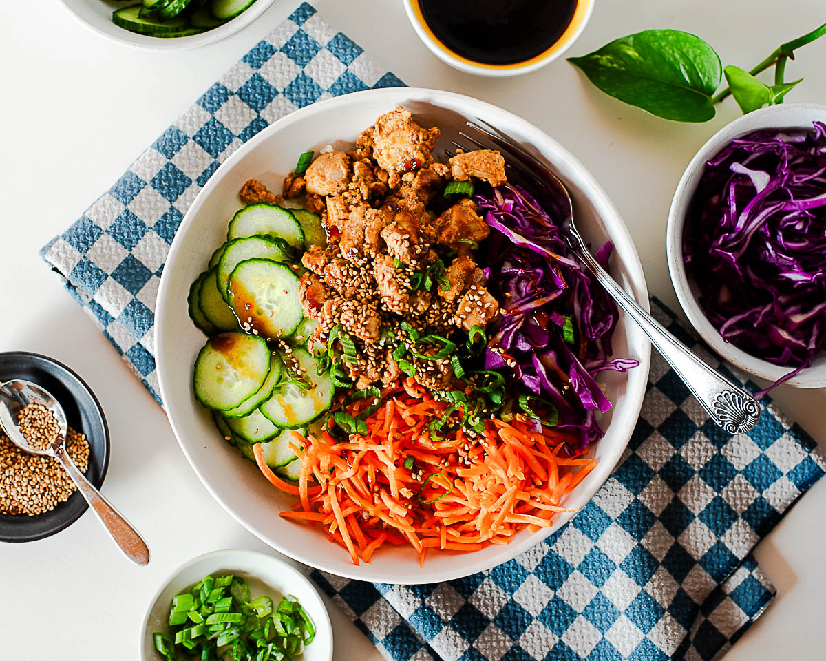Soy sauce, brown sugar, gochujang, sesame oil, garlic, ginger, sliced beef, scallions, and cucumbers arranged on a tidy kitchen counter