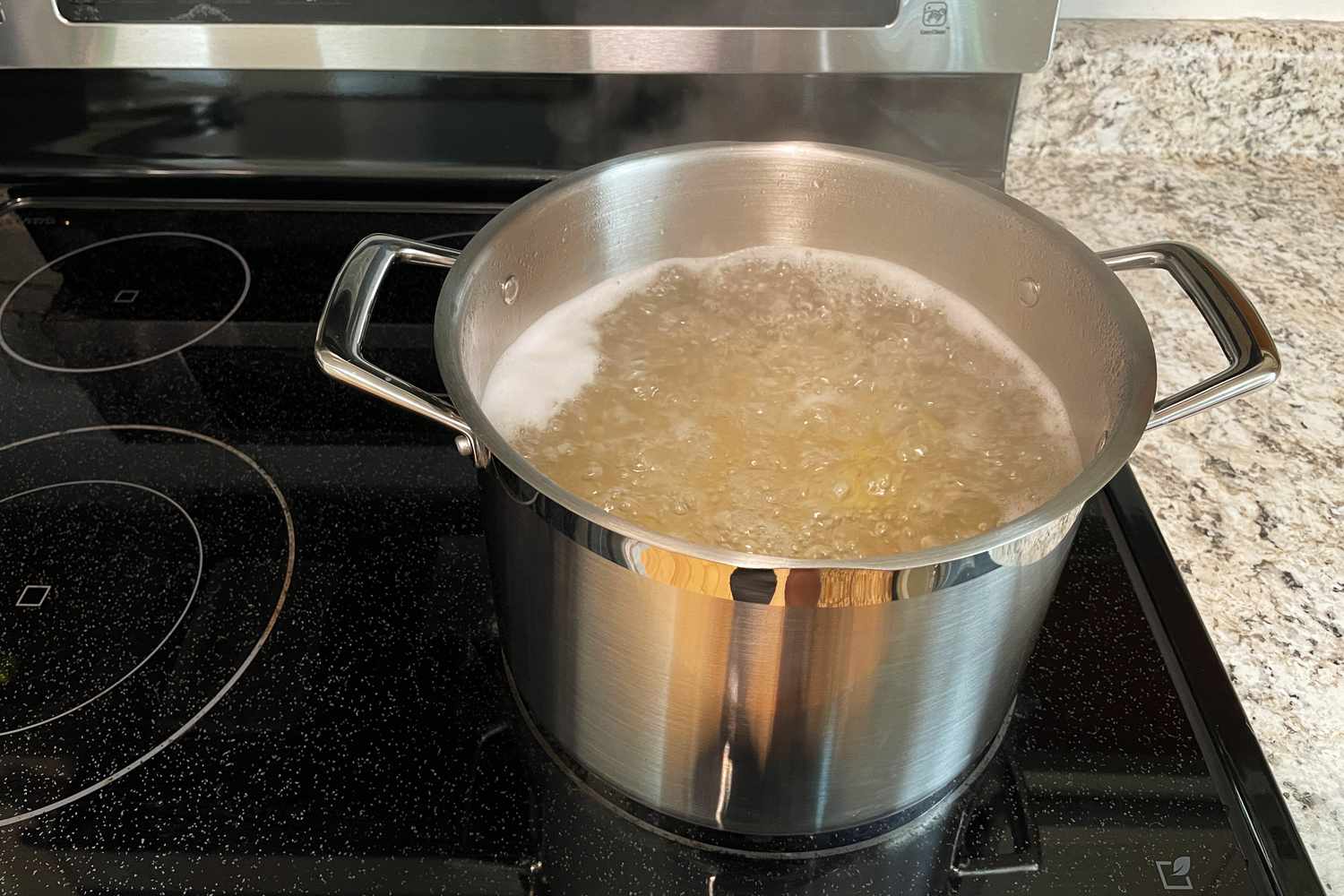 Spaghetti boiling in a large pot of water on a home stove, steam rising