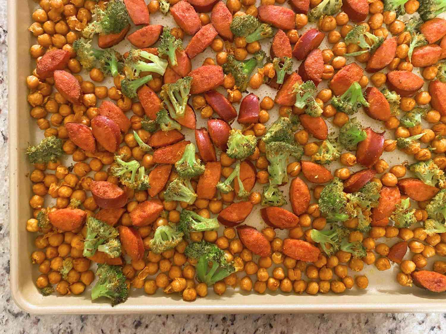 Spiced chickpeas roasting in a single layer on a sheet pan in a home oven