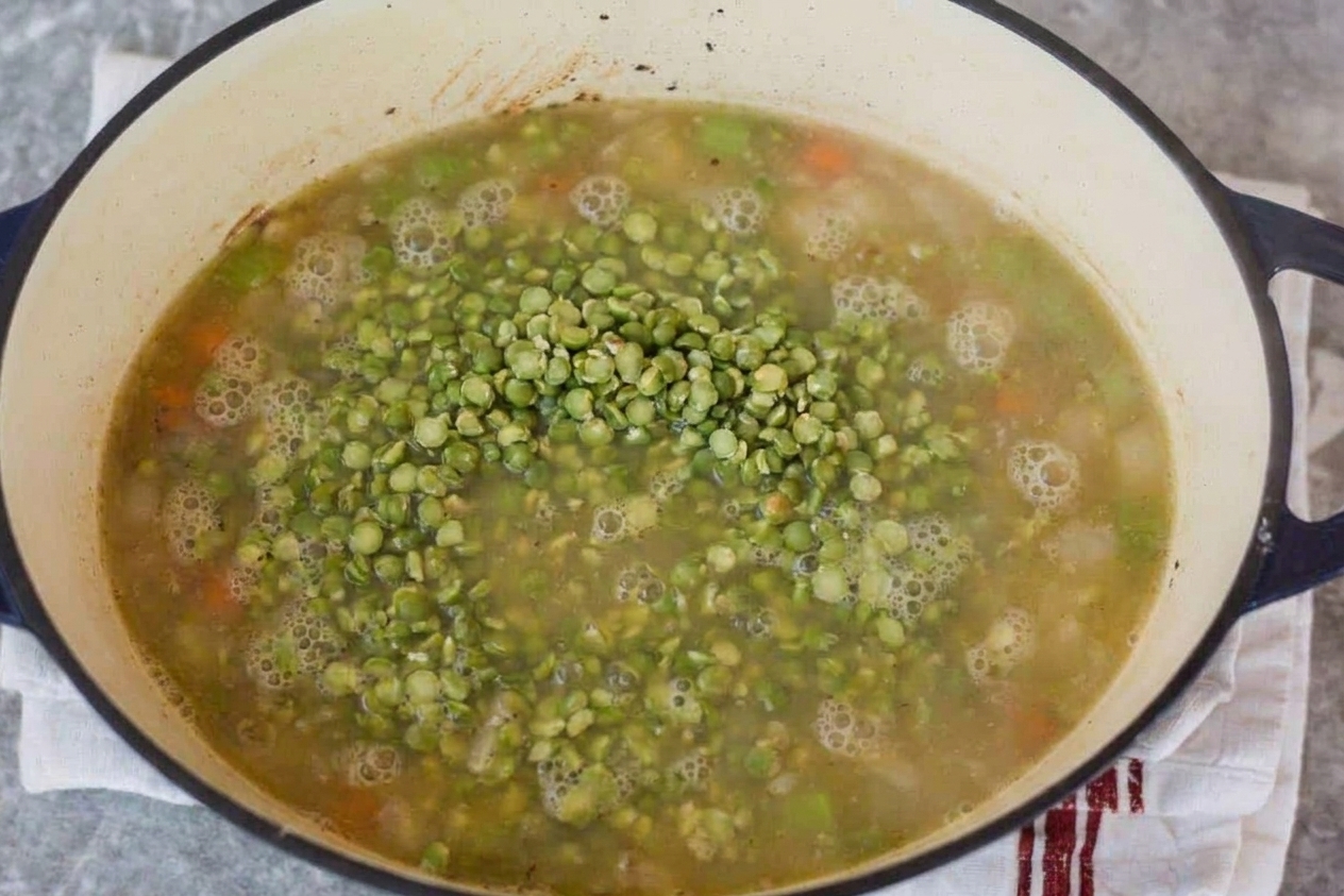 Split peas simmering in broth in a Dutch oven on the stove with gentle bubbles on the surface