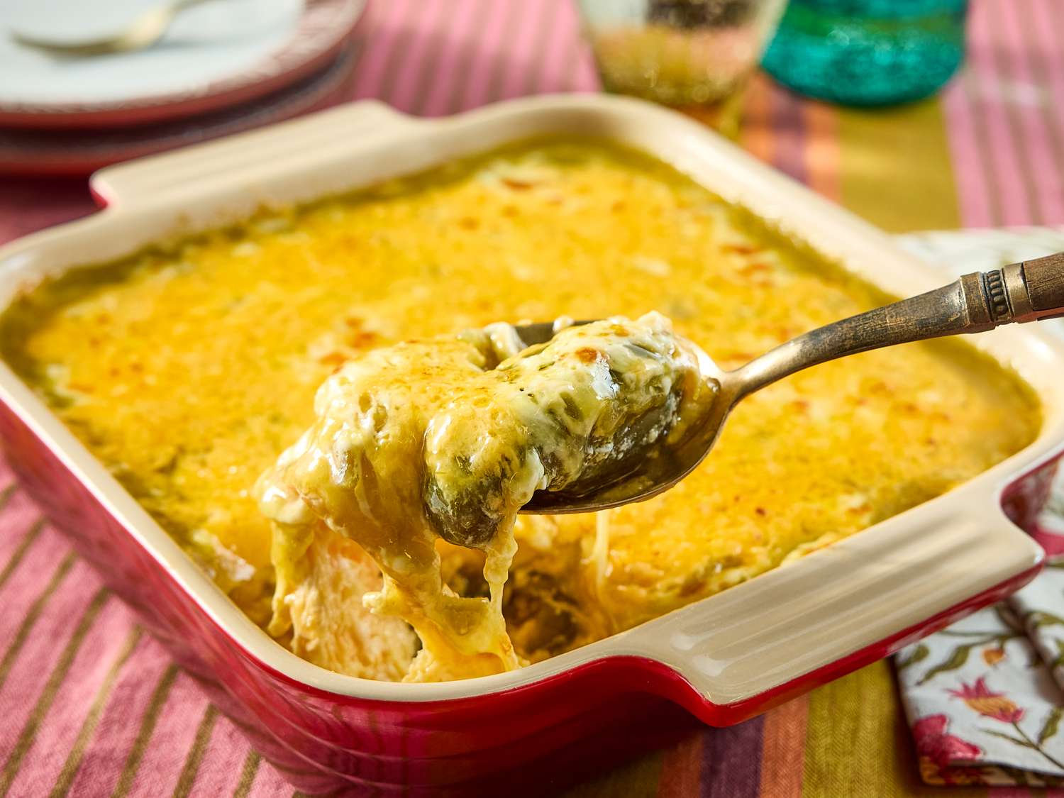 Square slices of chili relleno casserole packed into a glass meal prep container with a tight lid on a kitchen counter