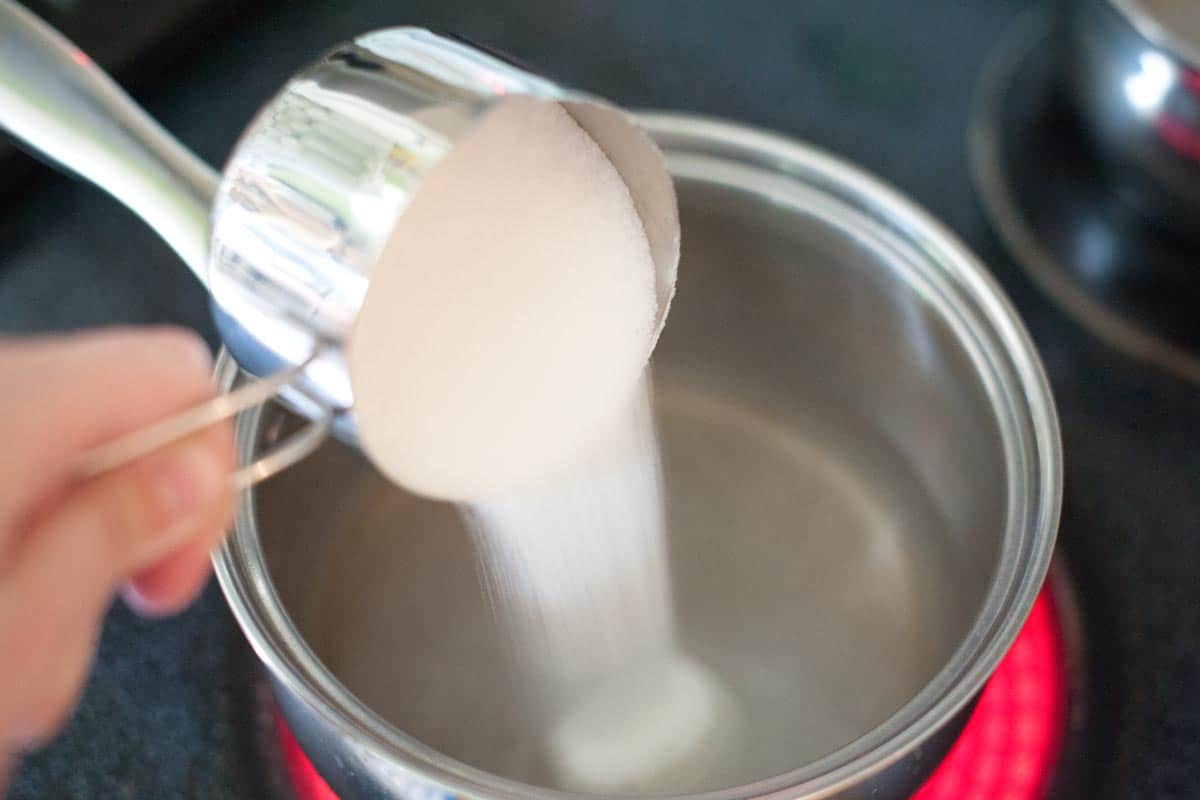 Sugar and water simmering in a small saucepan on a stovetop to make simple syrup