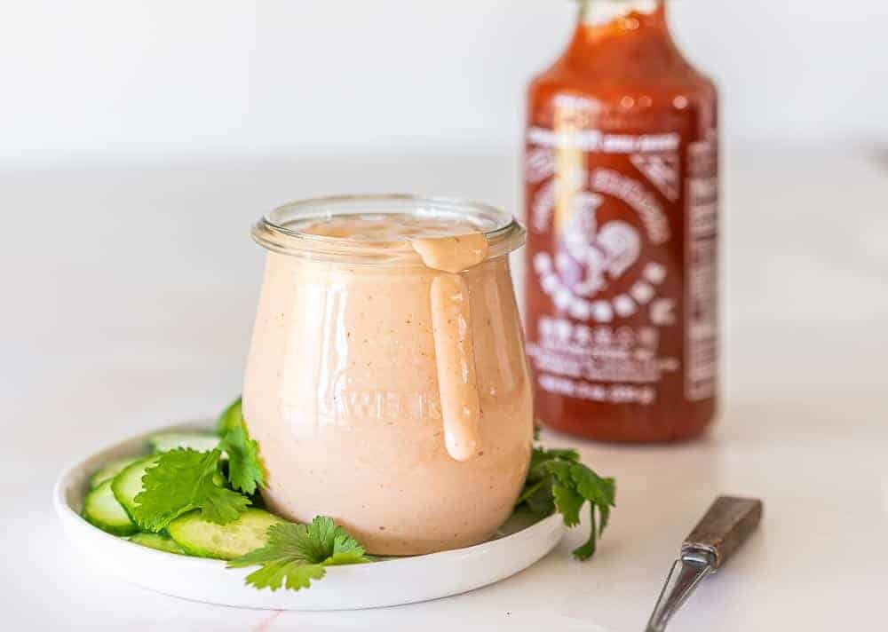 Sweet Thai chili sauce, sriracha, mayonnaise, and a lime arranged on a kitchen counter, ready to make a quick sauce