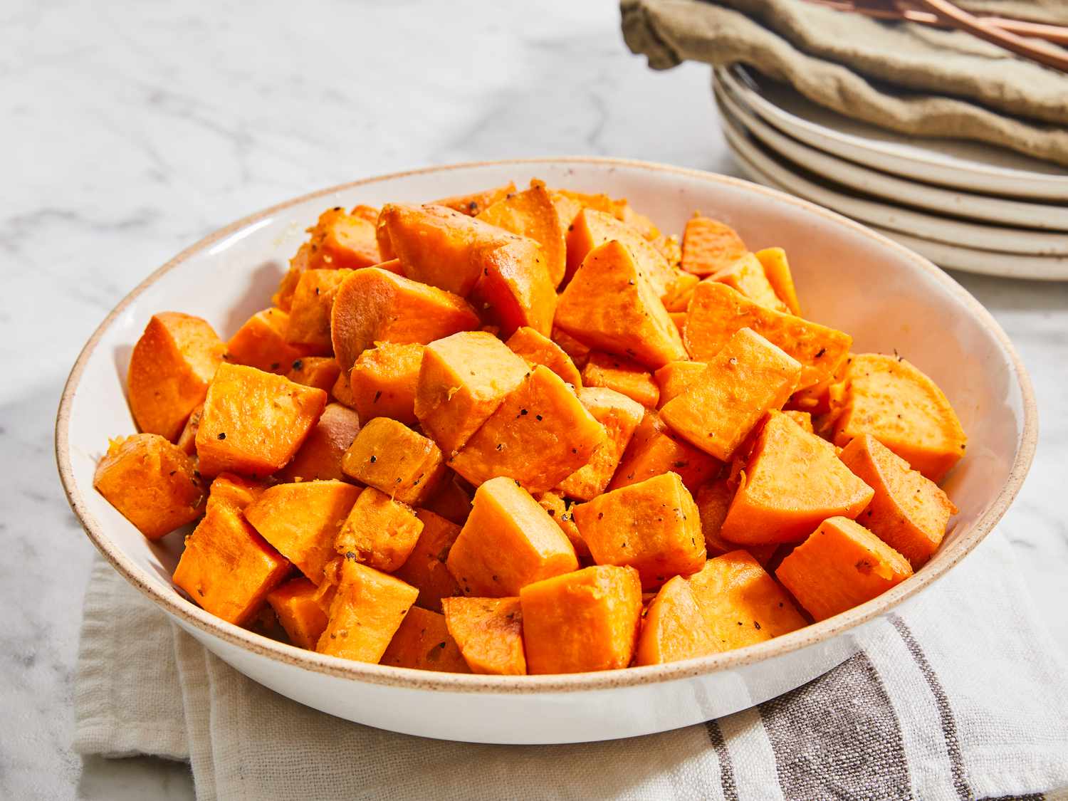 Sweet potatoes cut into evenly sized cubes in a mixing bowl on a kitchen counter, ready for seasoning