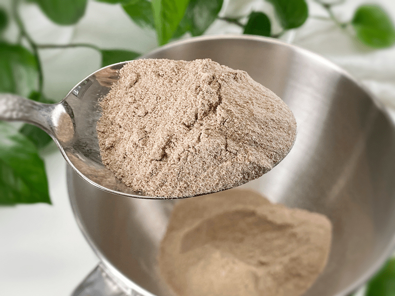 Teff flour, all purpose flour, a small bowl of yeast, salt, and a measuring cup of water arranged on a kitchen counter