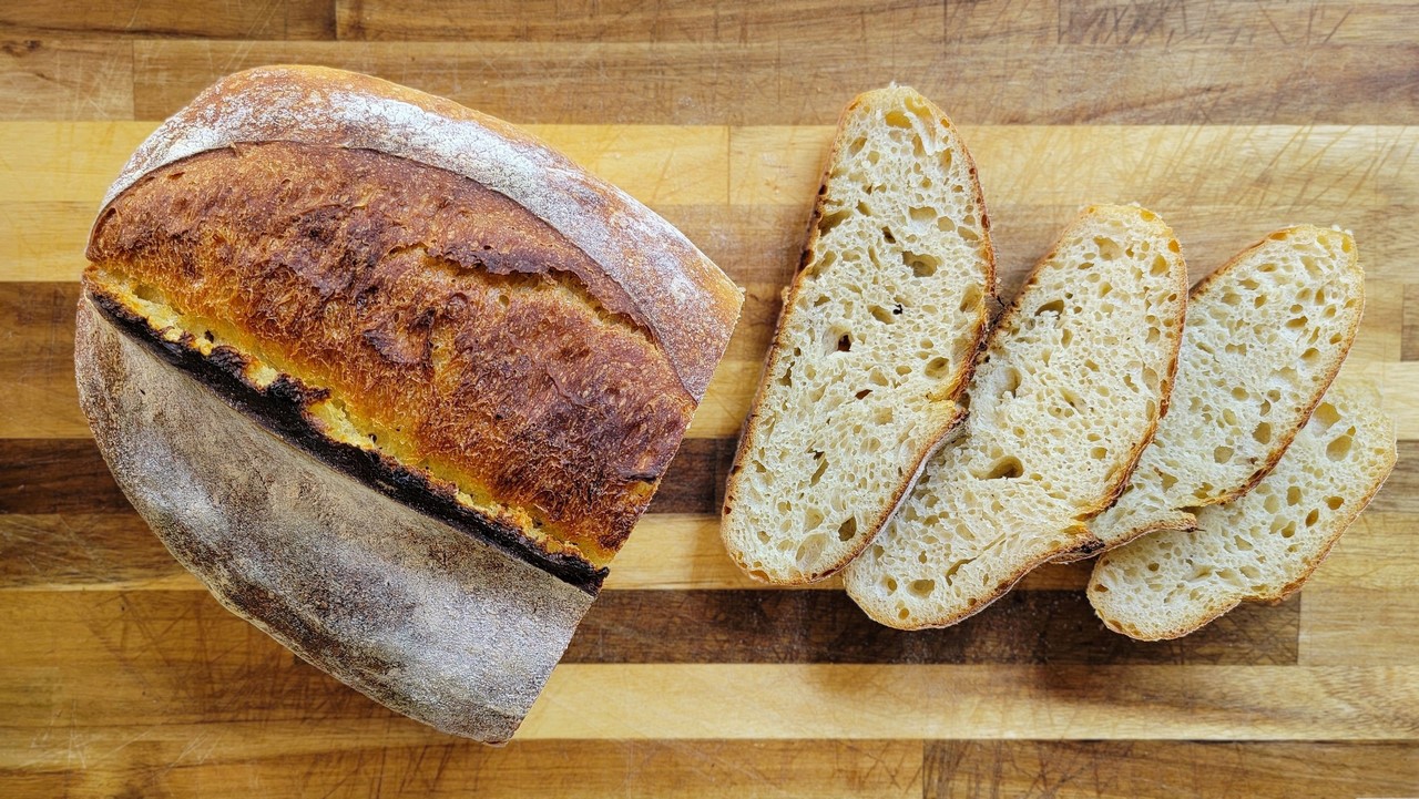 Thick slices of sourdough bread laid out on a wooden cutting board on a kitchen counter