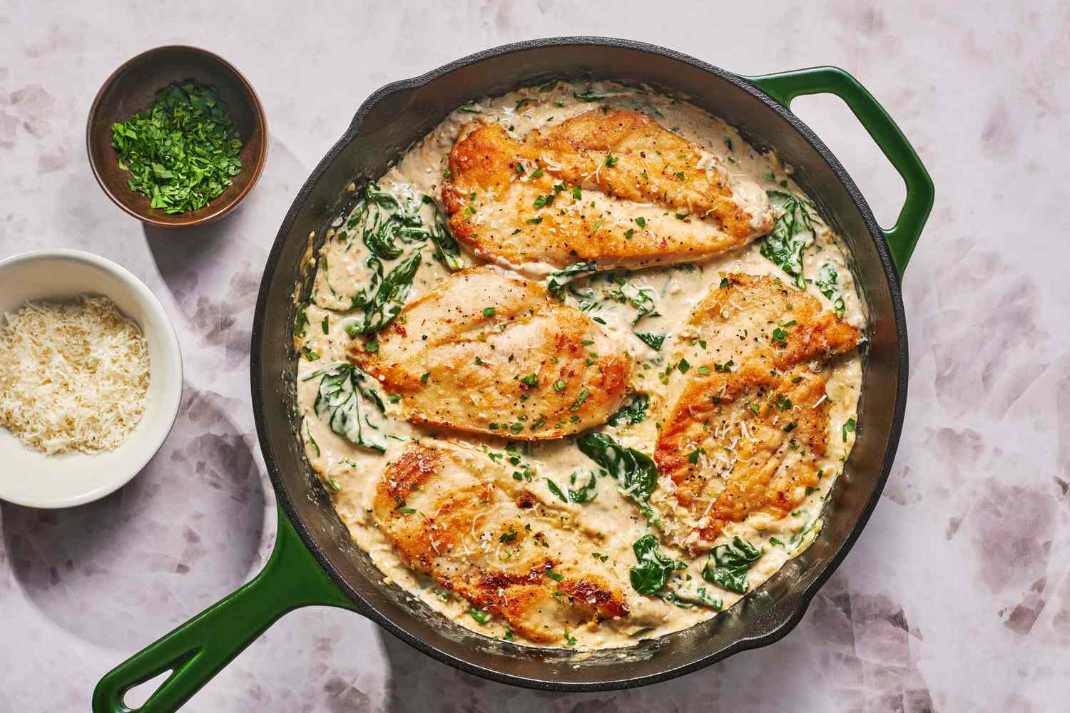 Thin chicken cutlets lightly coated in flour on a plate next to a shallow bowl of flour and seasonings on a kitchen counter