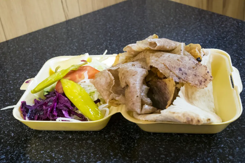 Thin slices of cooked doner meat stored in a glass meal prep container with a tight lid on a kitchen counter