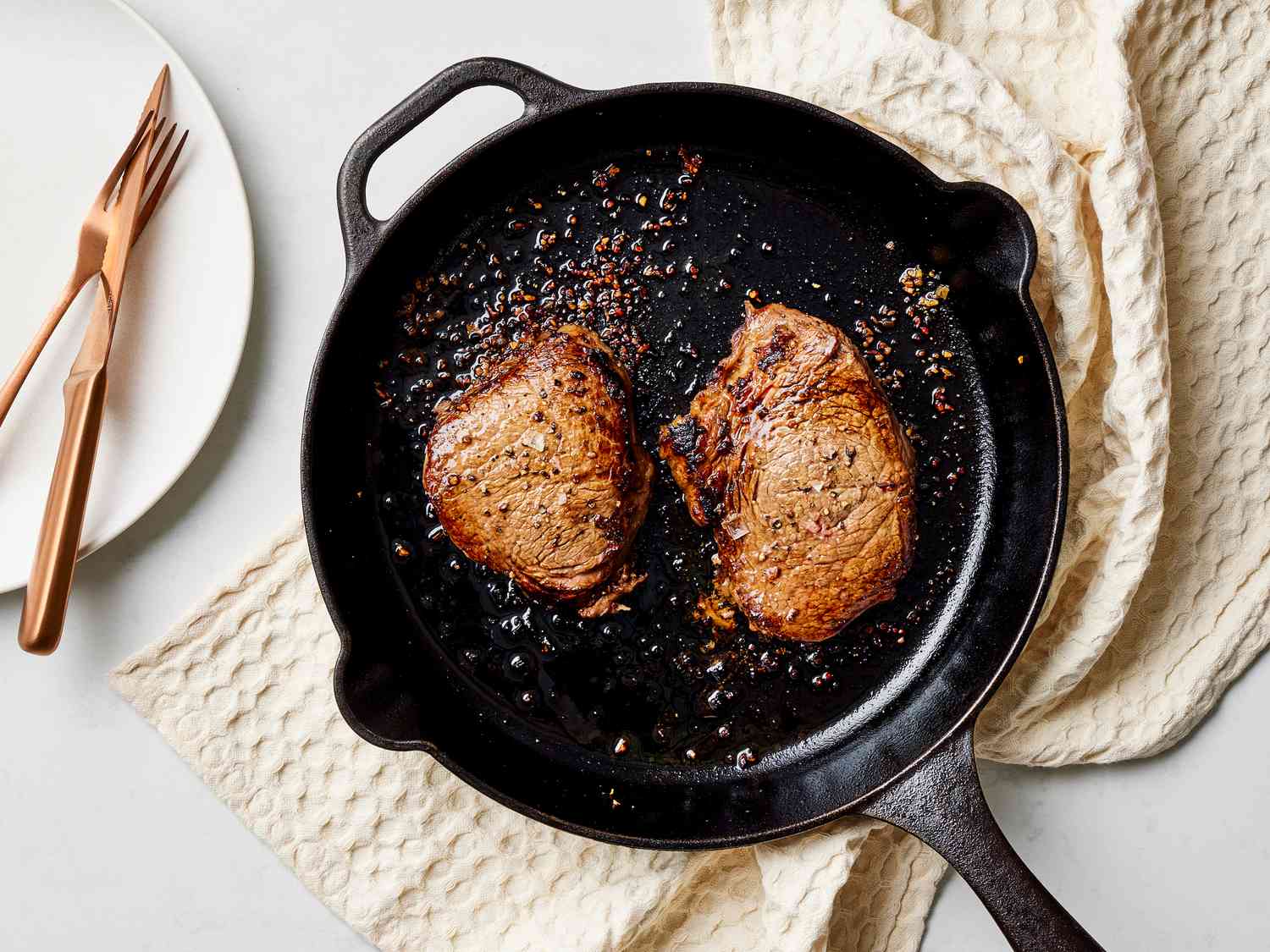 Thinly sliced steak searing in a hot cast iron skillet with browned edges forming