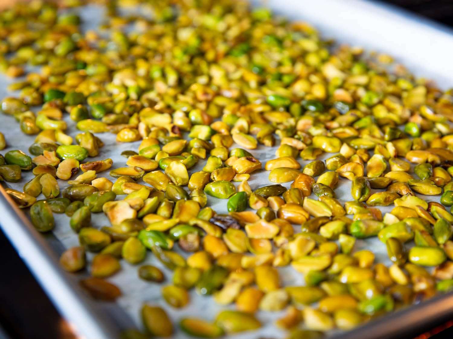 Toasted pistachios spread in a single layer on a baking sheet on a kitchen counter