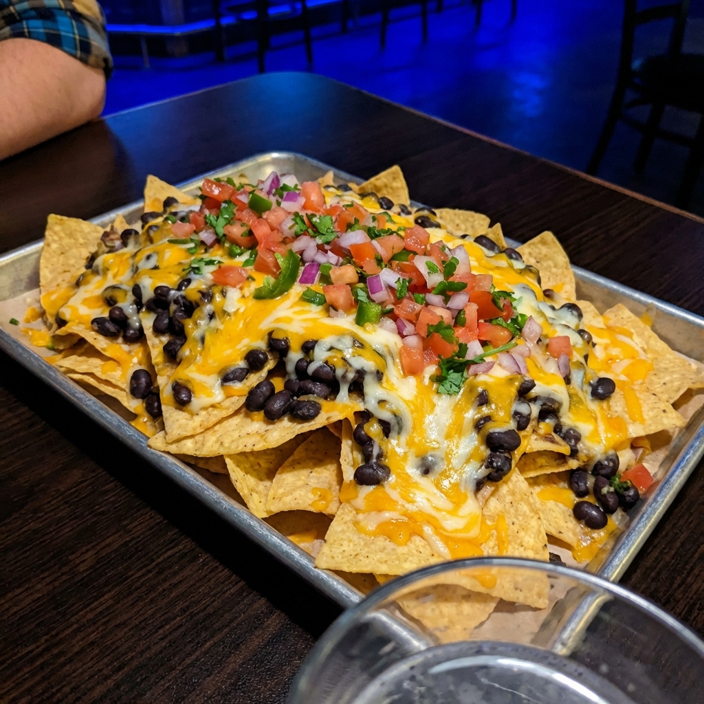 Tray of nachos topped with melted cheese, black beans, and fresh pico de gallo