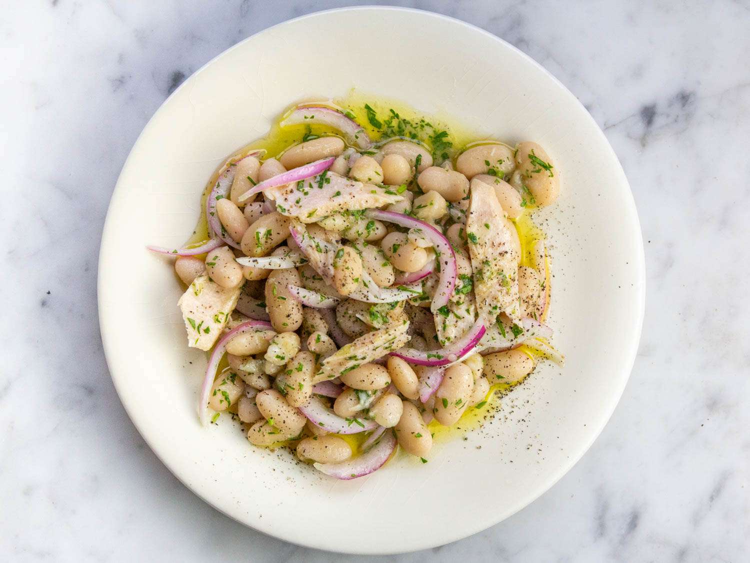 Tuna, cannellini beans, red onion, capers, lemon, and parsley measured out on a kitchen counter for a simple salad