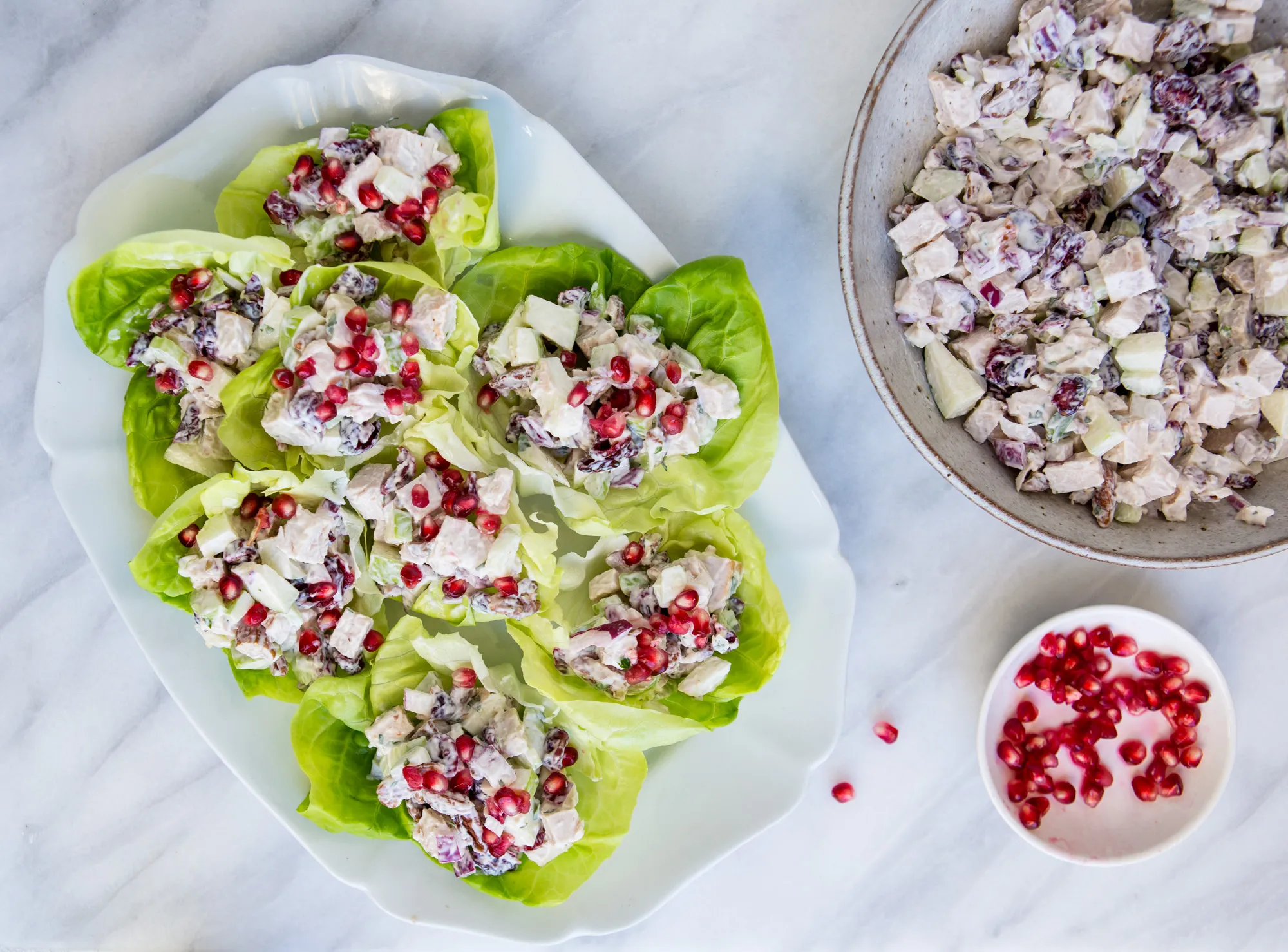 Turkey salad piled into crisp romaine lettuce cups on a platter with lemon wedges on a kitchen table