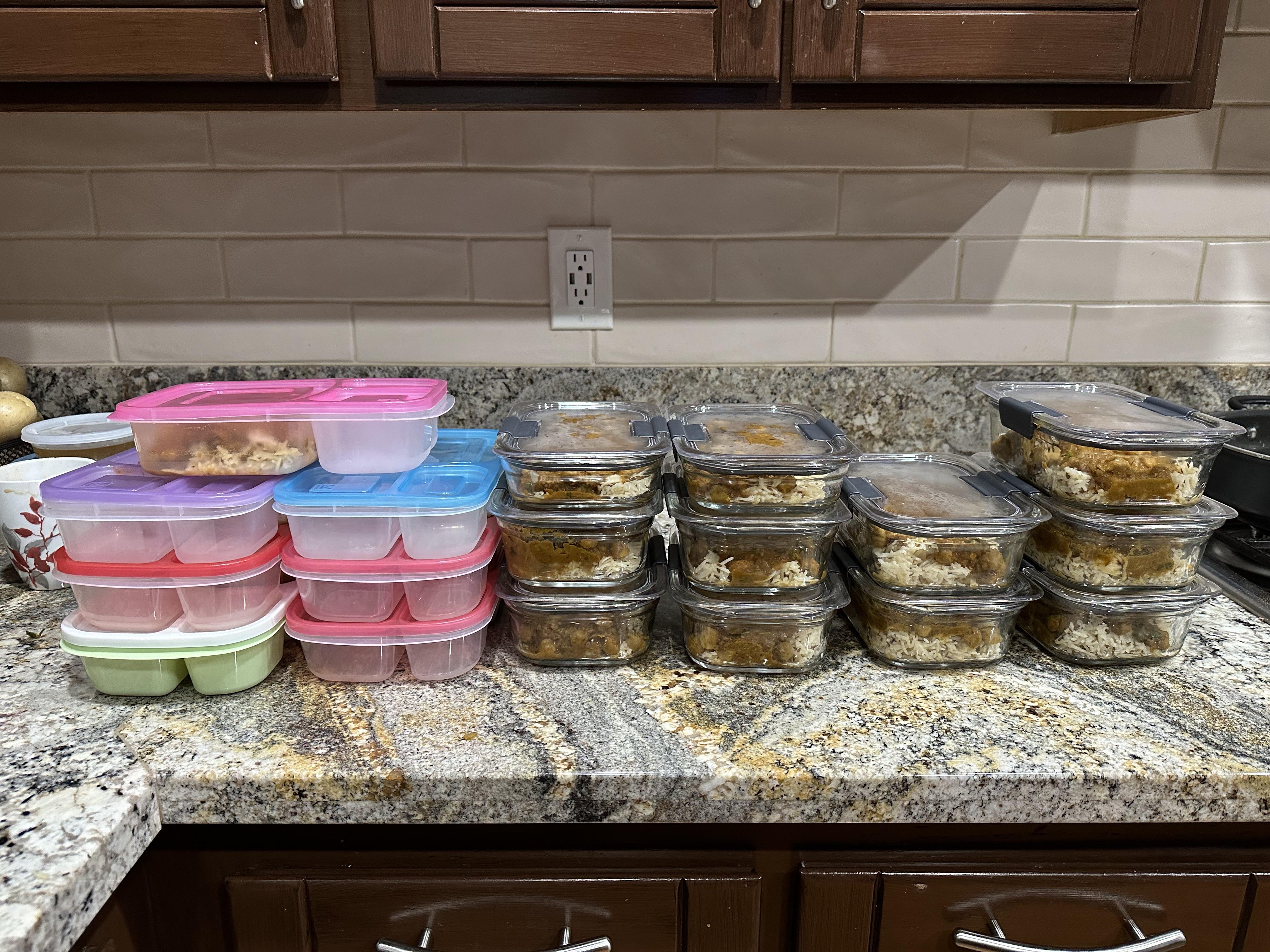 Two glass meal prep containers filled with chana curry, one container paired with basmati rice, set on a kitchen counter