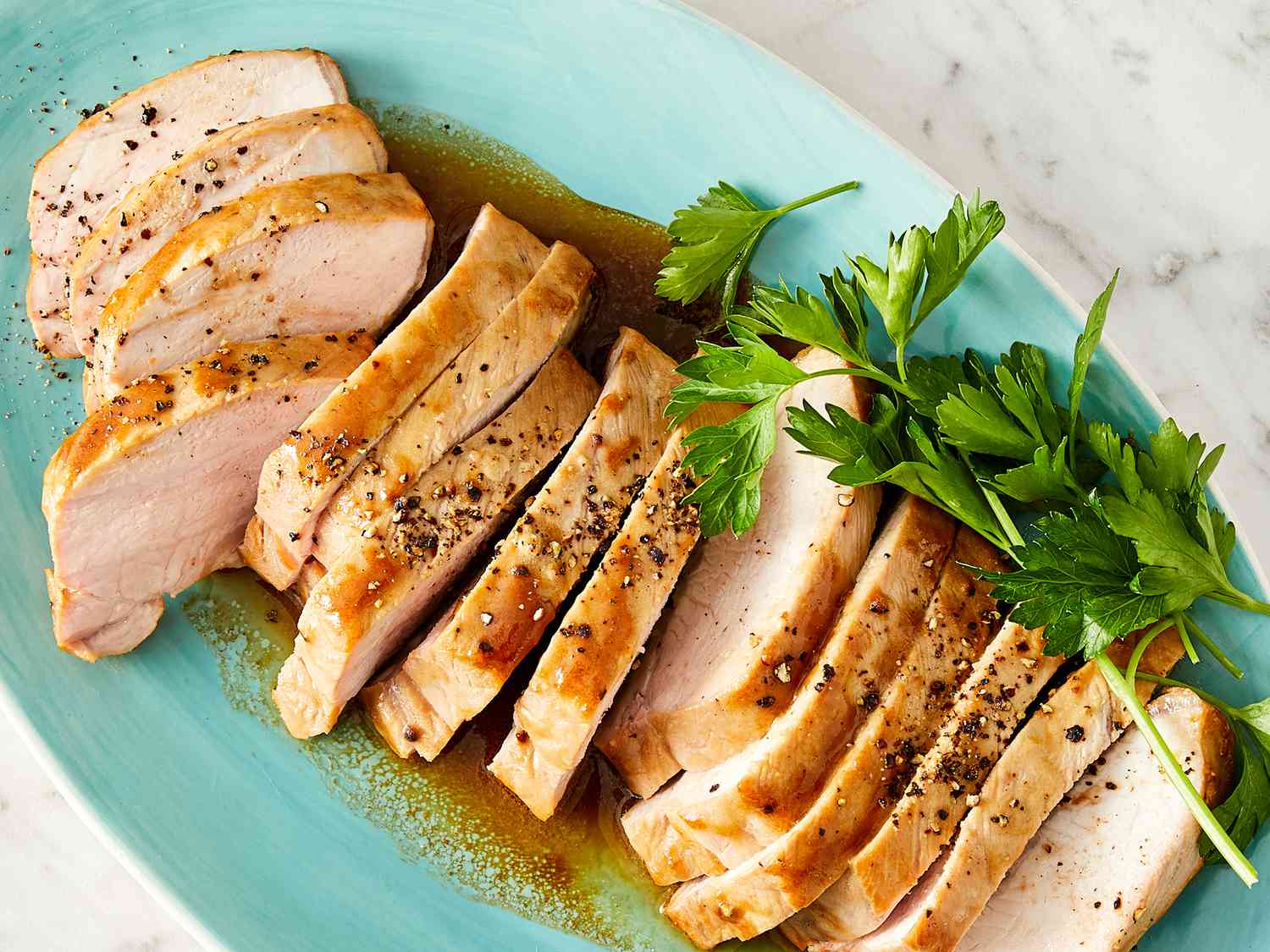 Two pork tenderloins seasoned with salt, pepper, and paprika on a wooden cutting board next to minced garlic and measured sauce ingredients