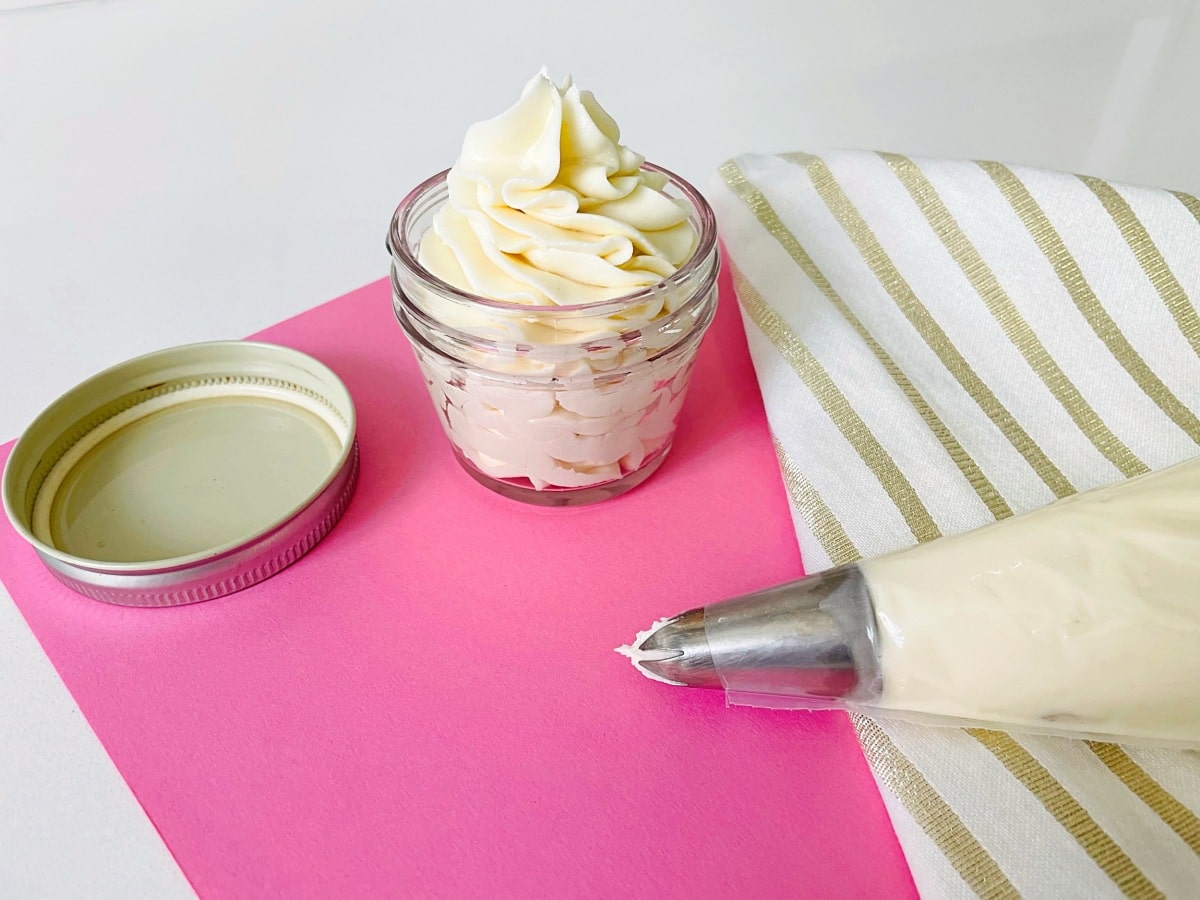 Vanilla buttercream stored in an airtight container with a spatula beside it