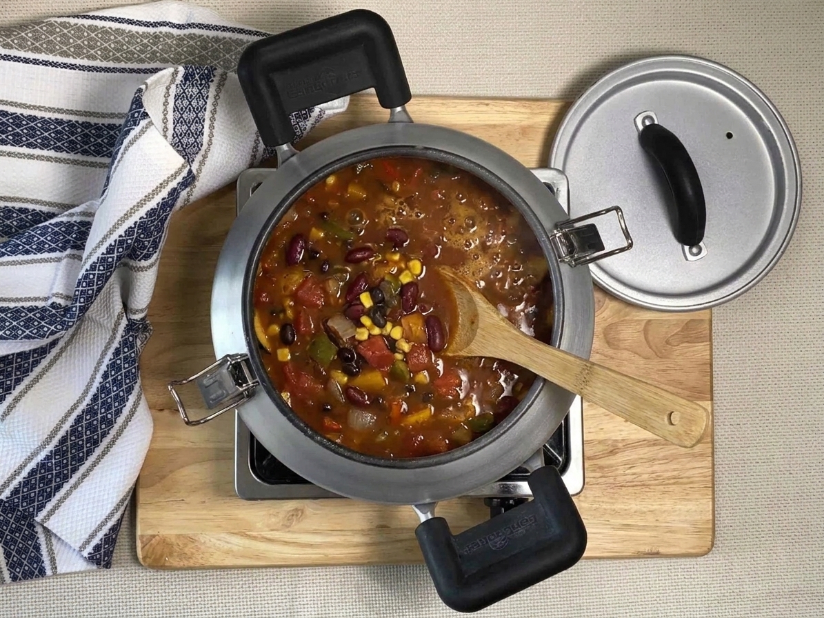 Veggie chili gently simmering in a large pot on the stove with small bubbles and visible beans and vegetables