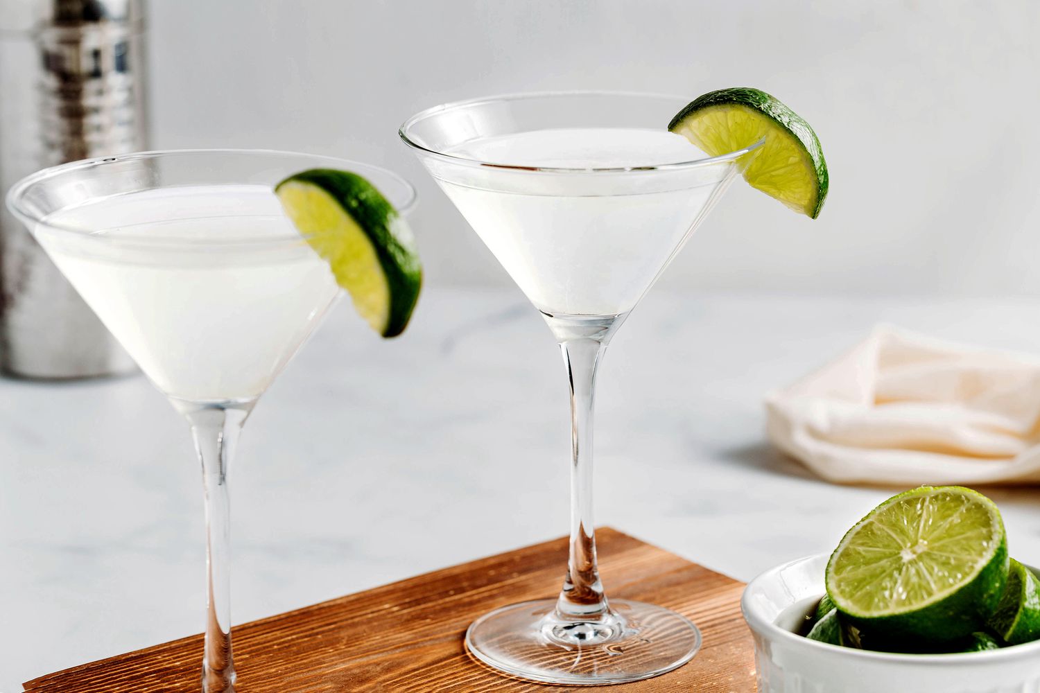 Vodka, triple sec, and fresh limes arranged with a jigger and cocktail shaker on a tidy kitchen counter under warm light