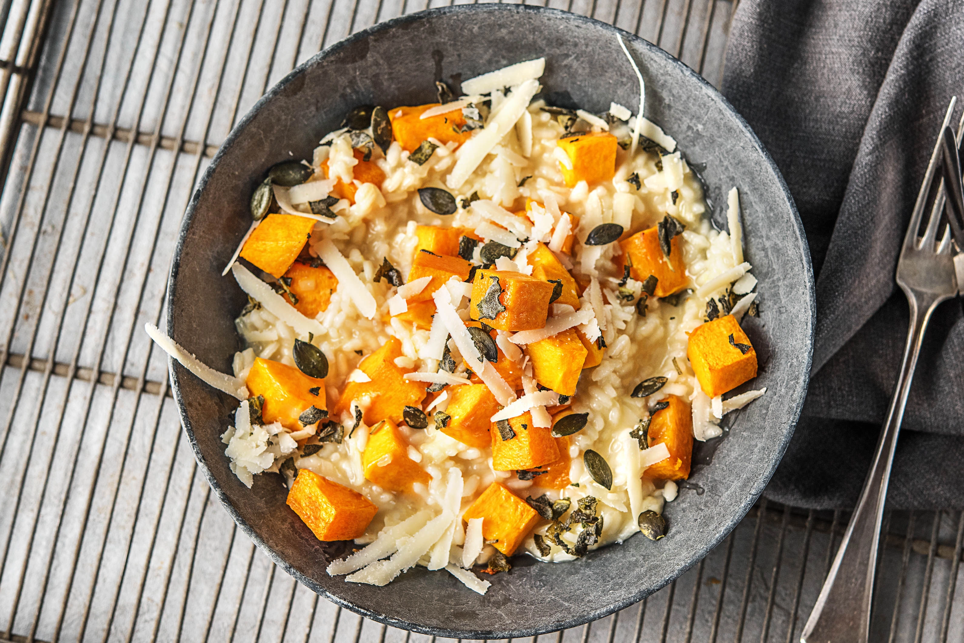 Whole butternut squash, arborio rice, Parmesan, onion, garlic, sage, butter, and broth arranged on a clean kitchen counter in warm natural light