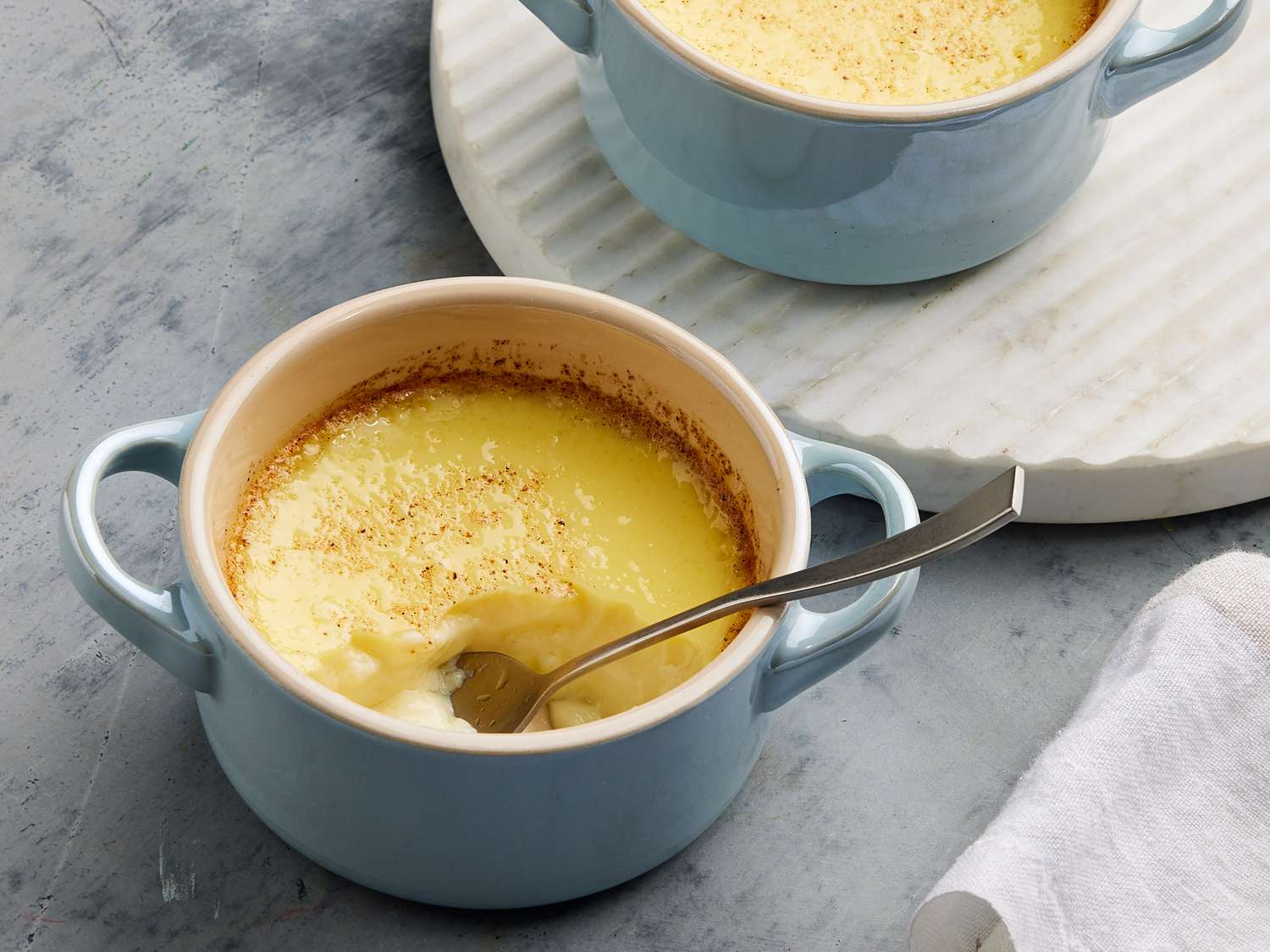 Whole eggs, egg yolks, sugar, milk, cornstarch, butter, and vanilla arranged on a clean kitchen counter in natural light